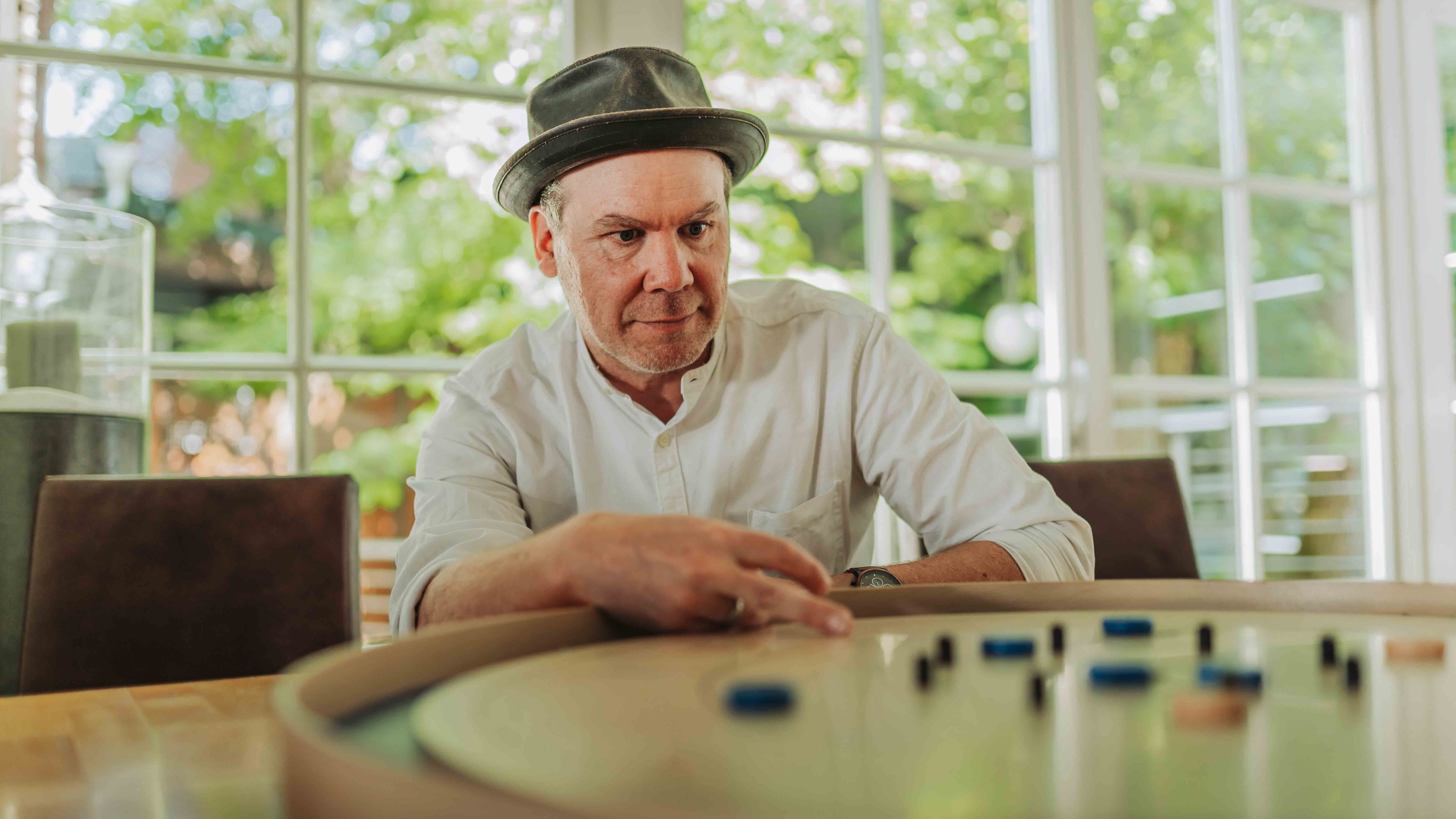 Mann mit Hut spielt Alea Alternativ S 35 Brettspiel am Tisch