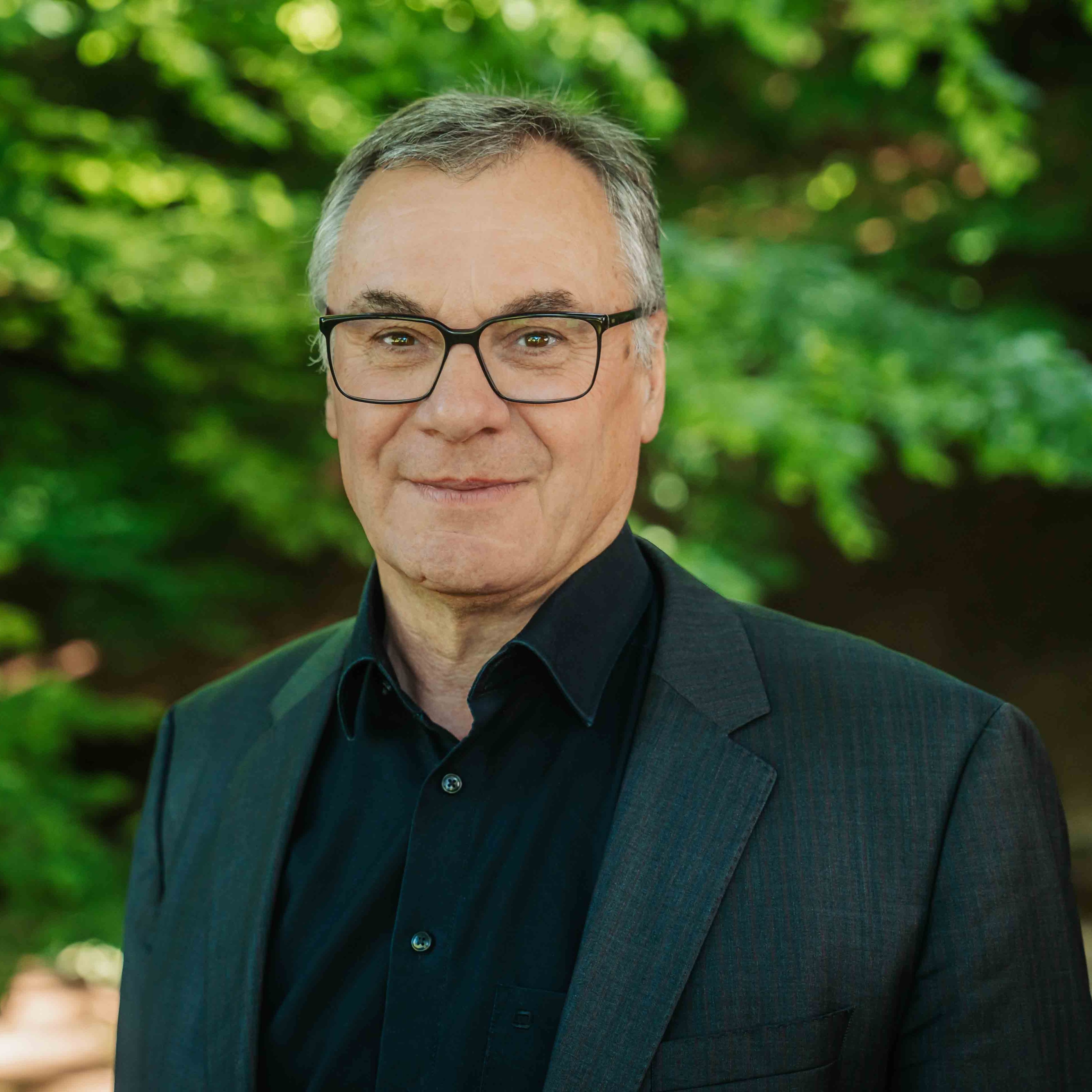 Alea Portrait eines Mannes im Anzug vor grünem Hintergrund