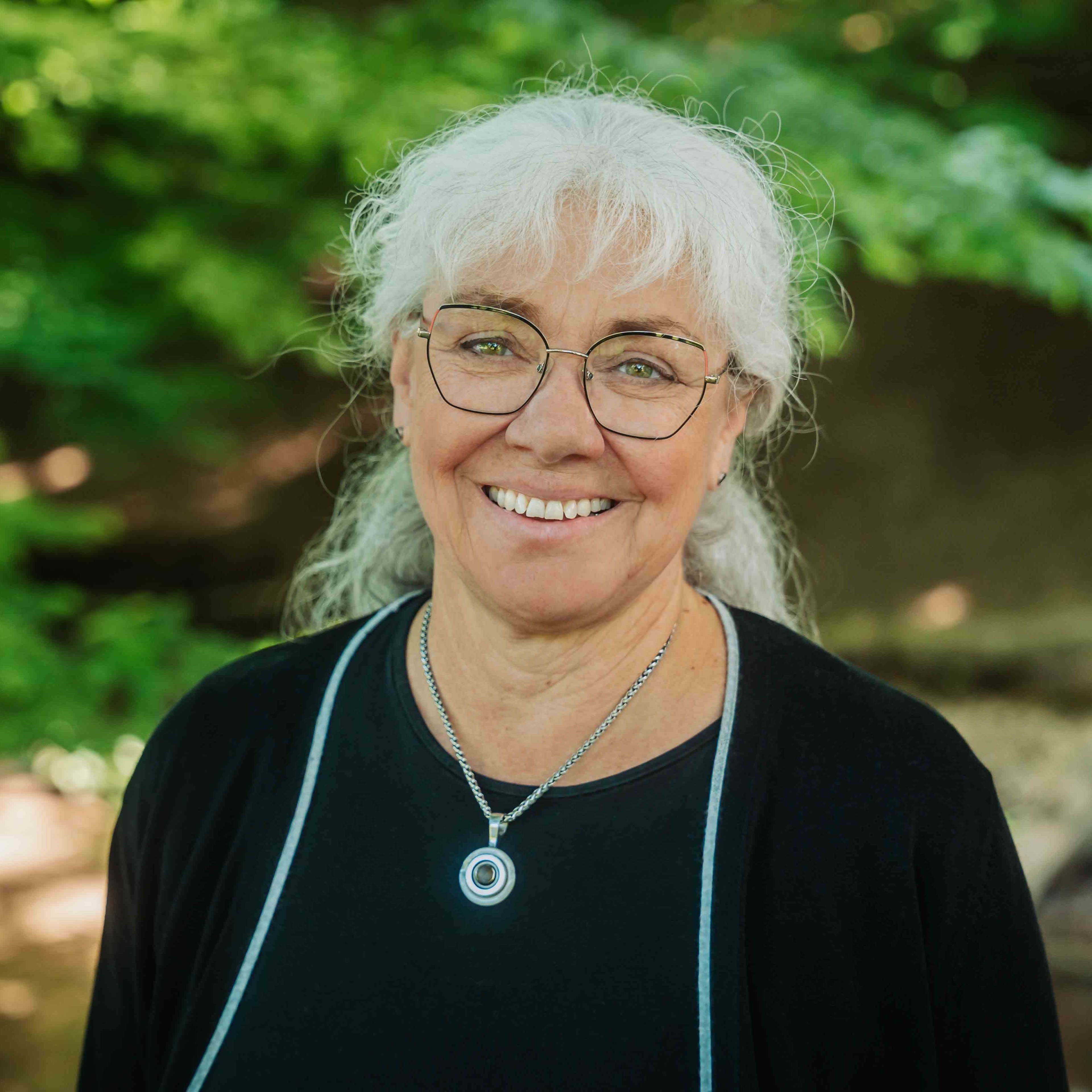 Alea Portrait S-39 – ältere Frau mit weißem Haar und silberner Kette vor grünem Hintergrund