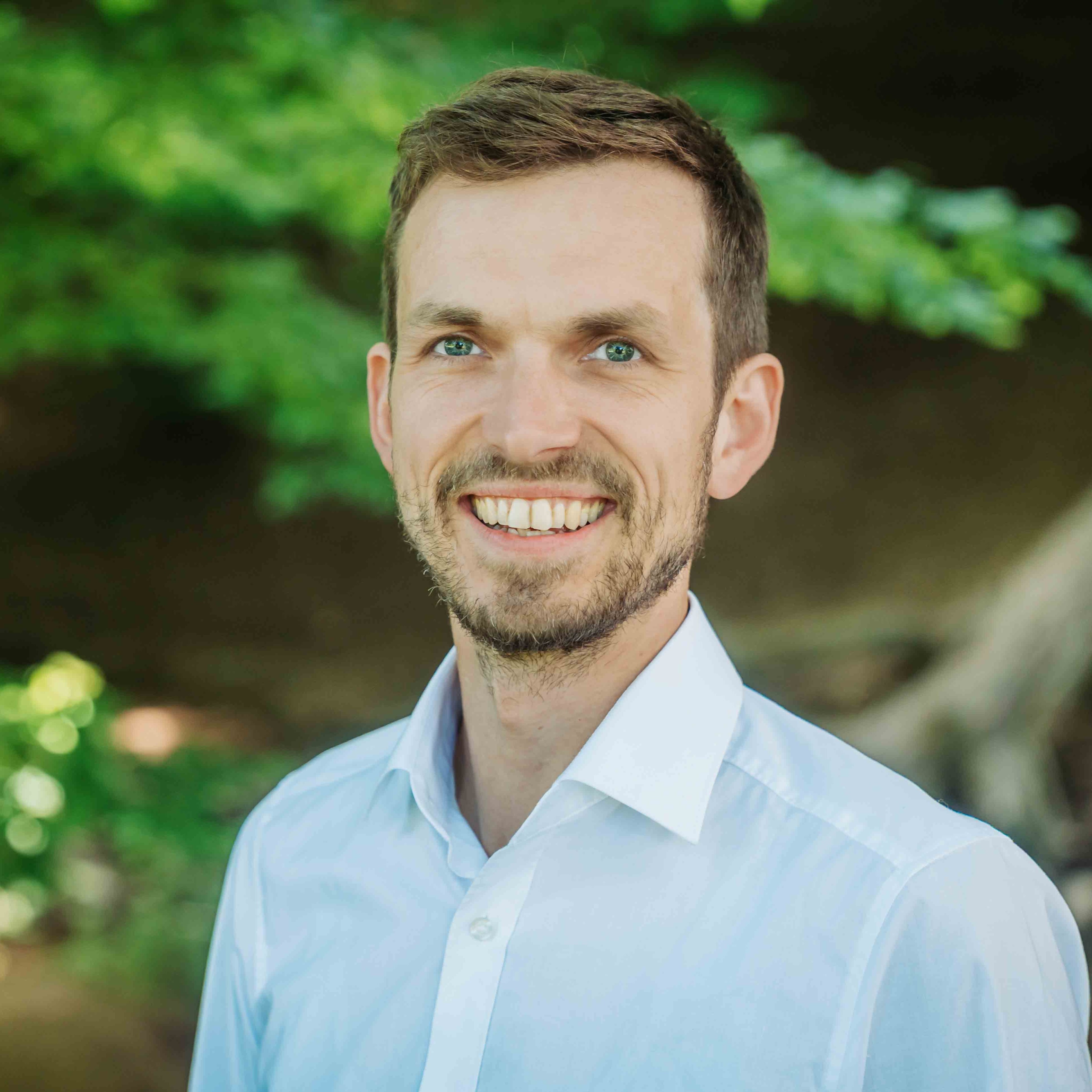 Alea Portrait eines Mannes im weißen Hemd vor natürlichem Hintergrund