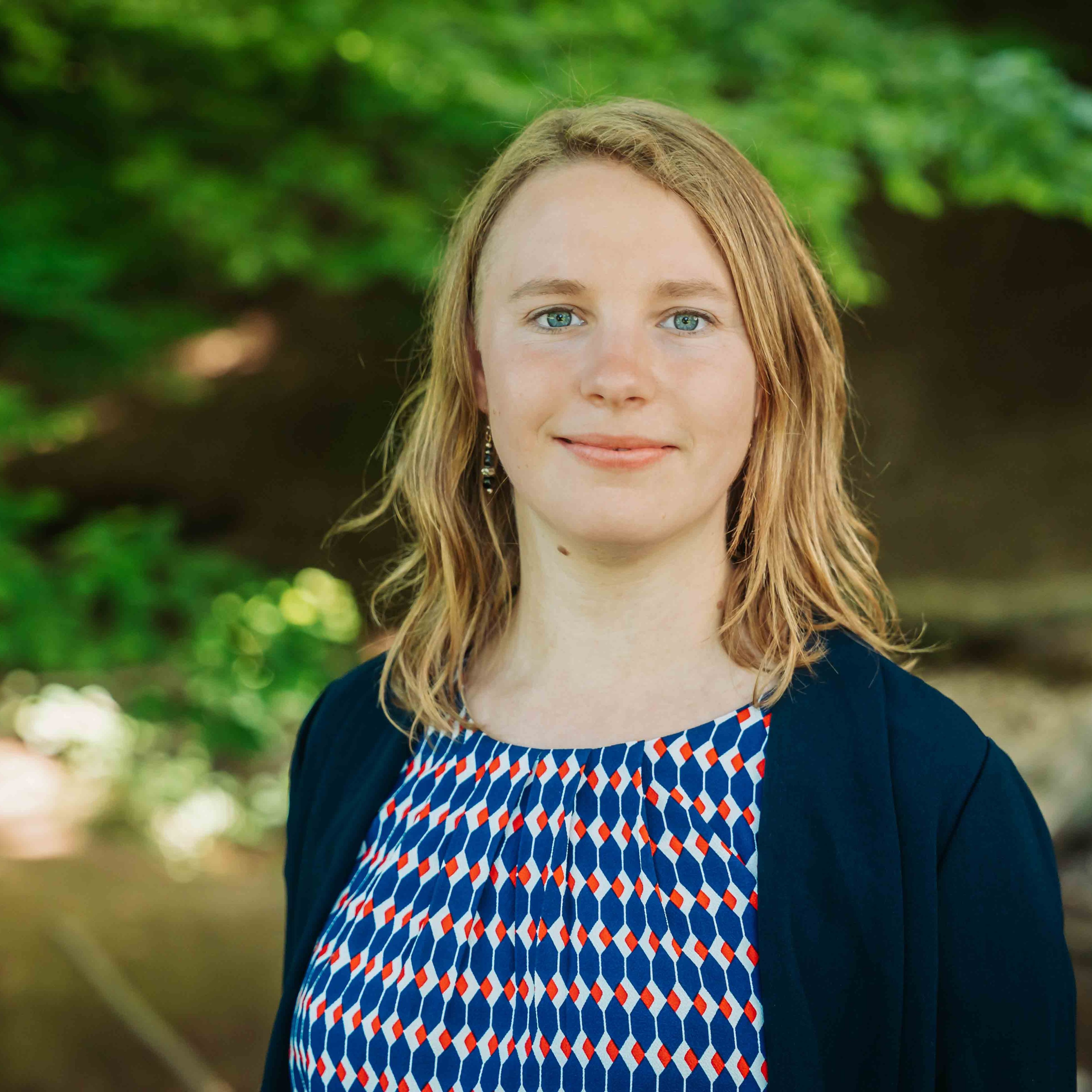 Alea Portrait im Freien mit gemustertem Kleid und grünem Hintergrund