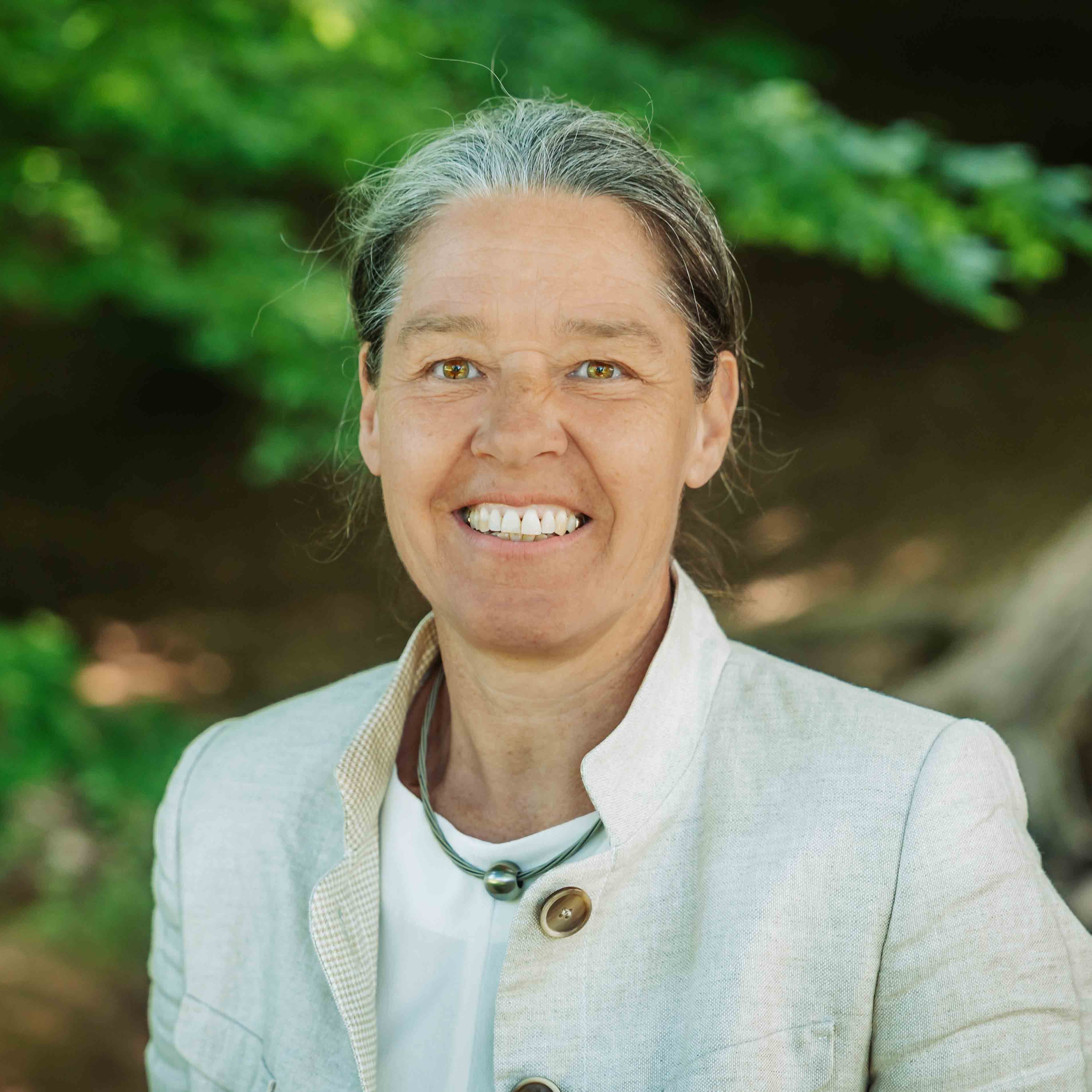 Portraitfoto von Alea im Freien, Person mit grauen Haaren und hellem Blazer