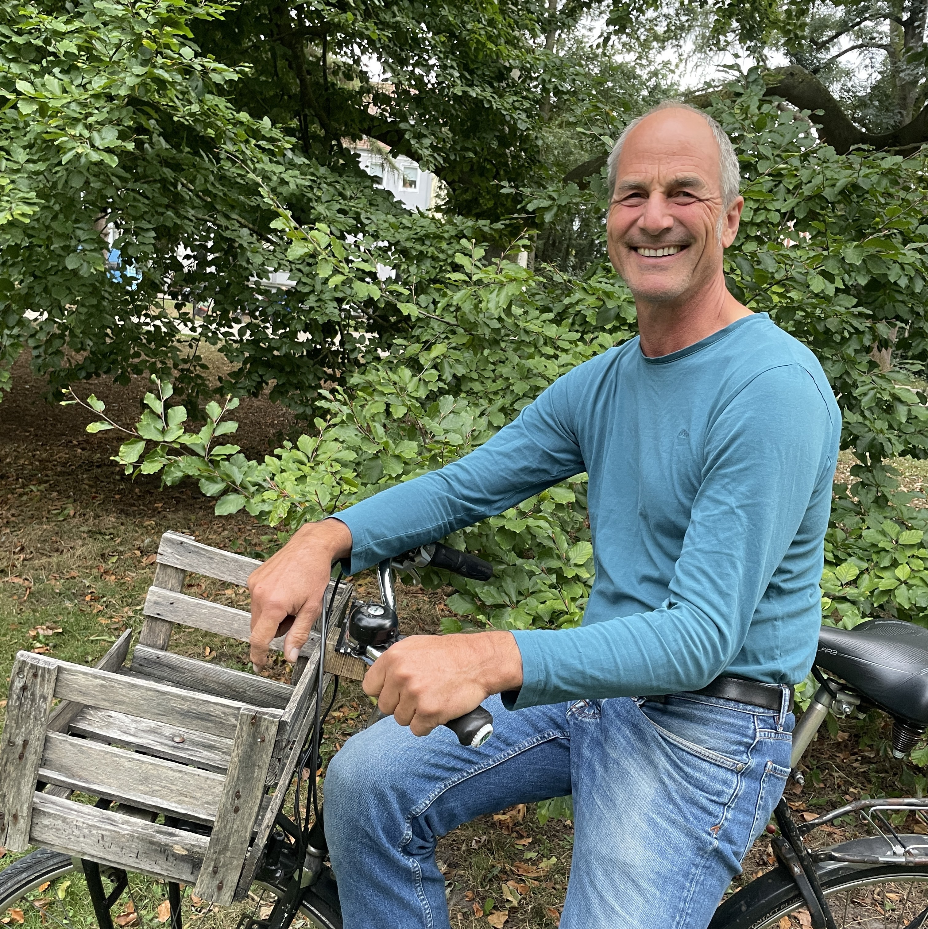 Christoph individuell auf einem Fahrrad mit Holzkiste im Grünen