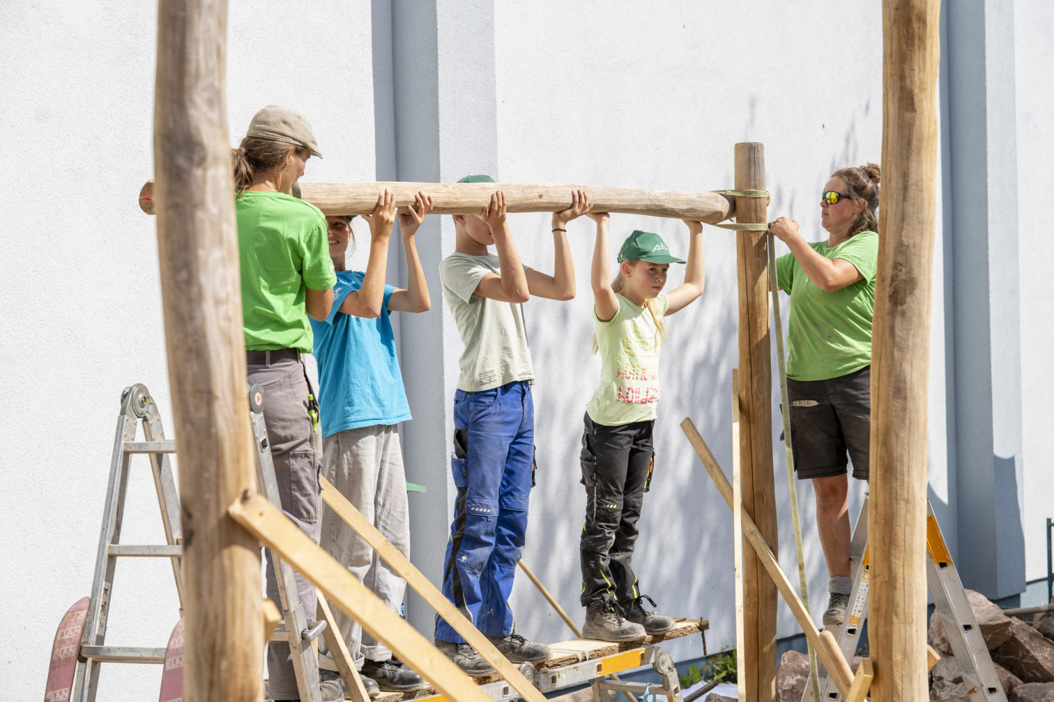 Kinder und Erwachsene beim gemeinsamen Holzbau auf einer Baustelle im Freien