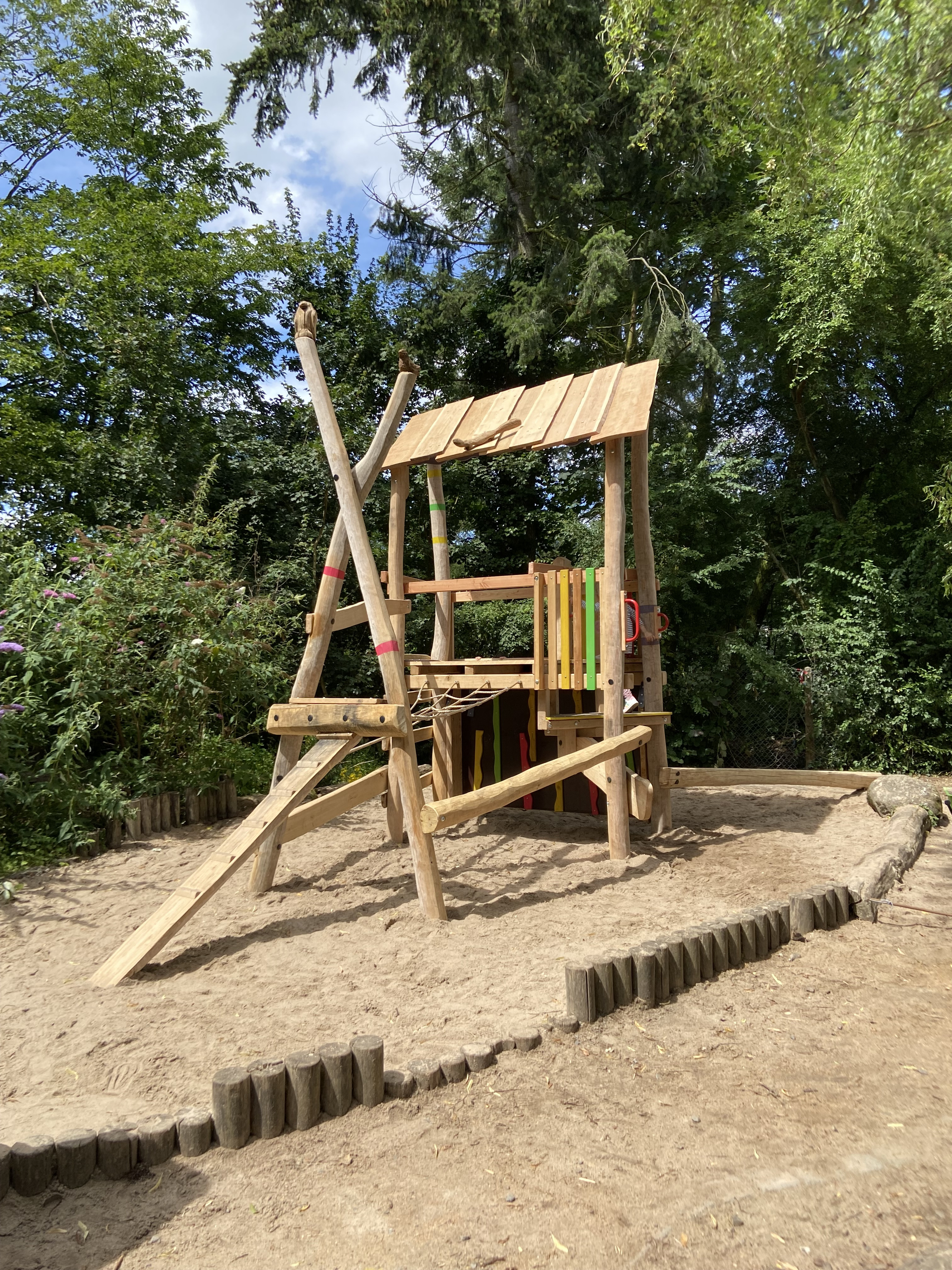 Holzspielplatz mit Klettergerüst im Sandkasten im Grünen