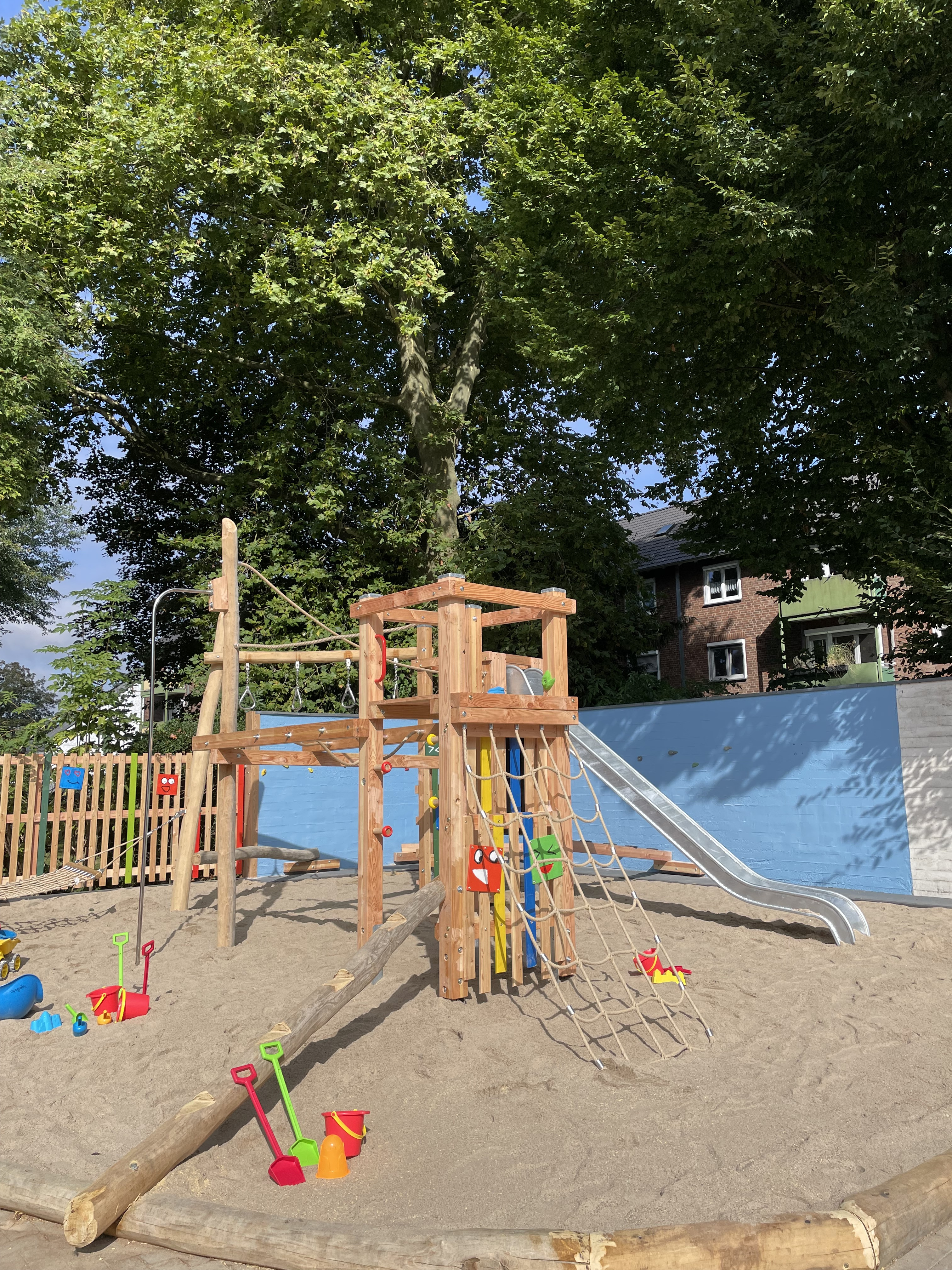 Moderner Spielplatz mit Klettergerüst, Rutsche und Sandspielzeug im Sandbereich
