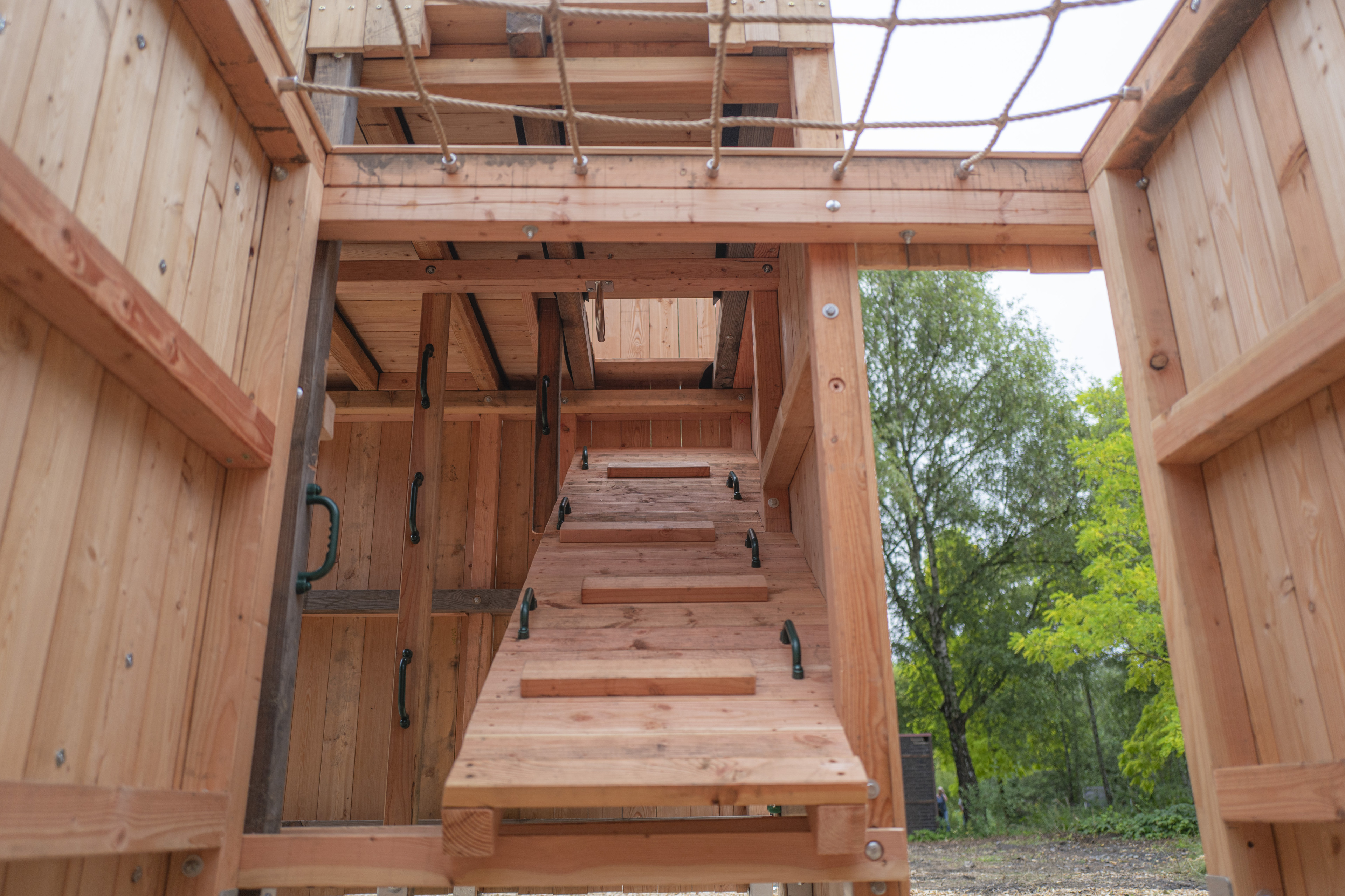 Holz-Klettergerüst mit Kletterwand und Seilnetz auf einem Spielplatz
