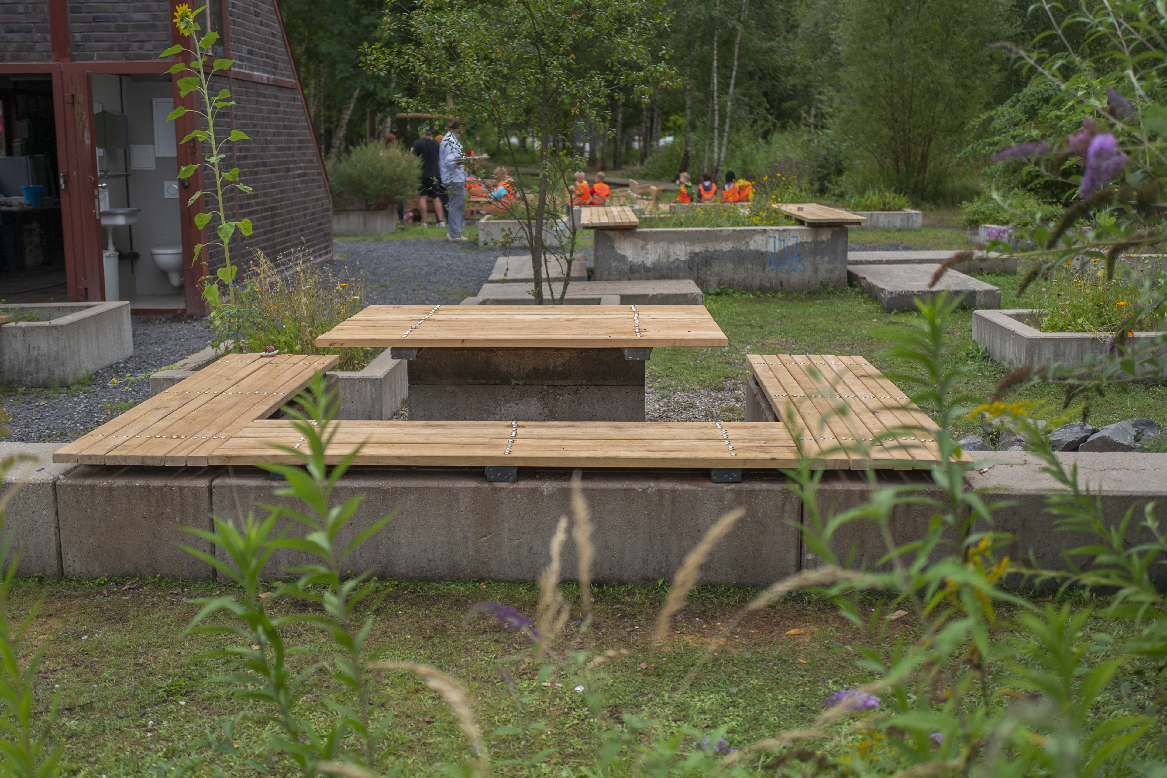 Holztische und Sitzbänke im Grünen mit Menschen im Hintergrund, l1280169