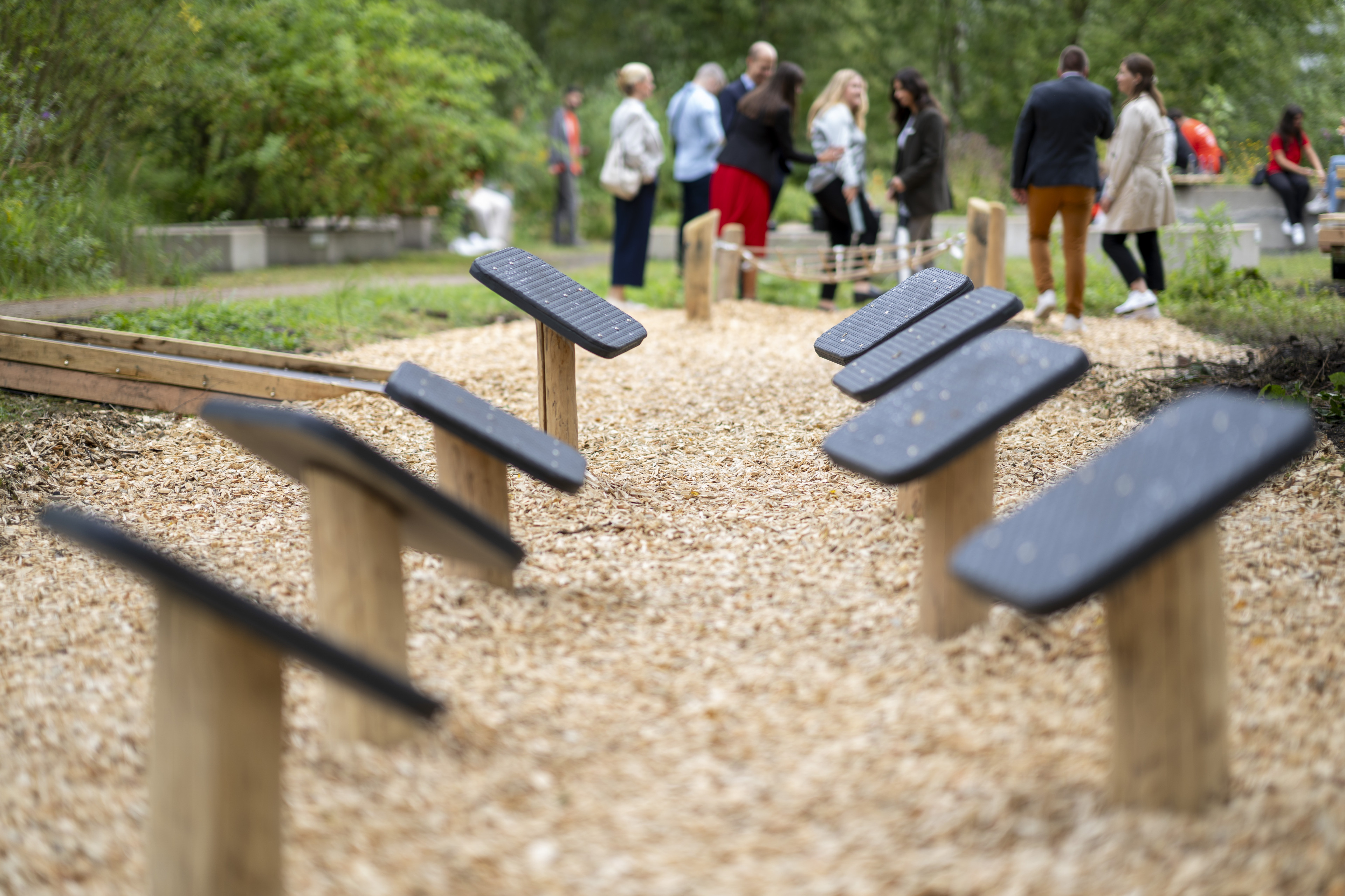Balancier-Parcours im Freien mit Holz und Gummi, im Hintergrund eine Gruppe von Menschen