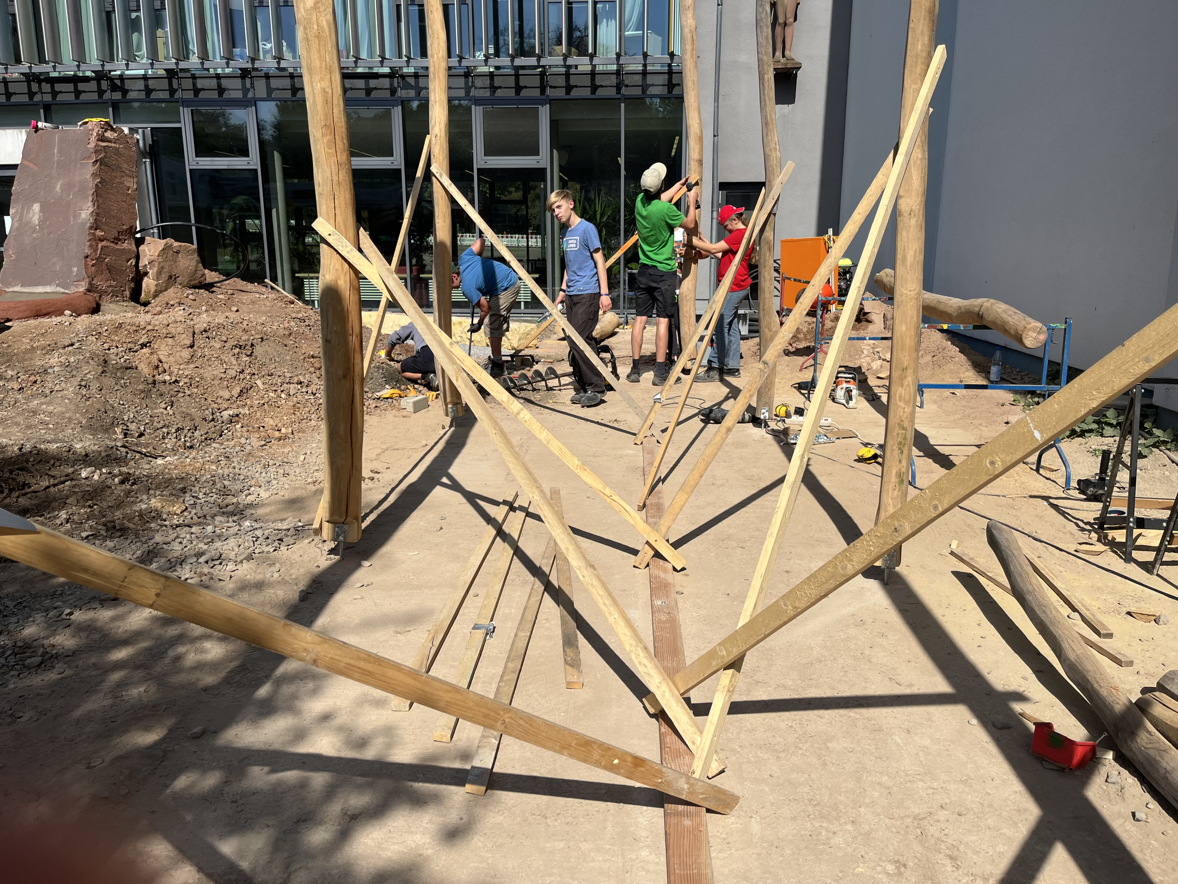 Bau einer Holzstruktur auf einer Baustelle mit mehreren Personen bei sonnigem Wetter