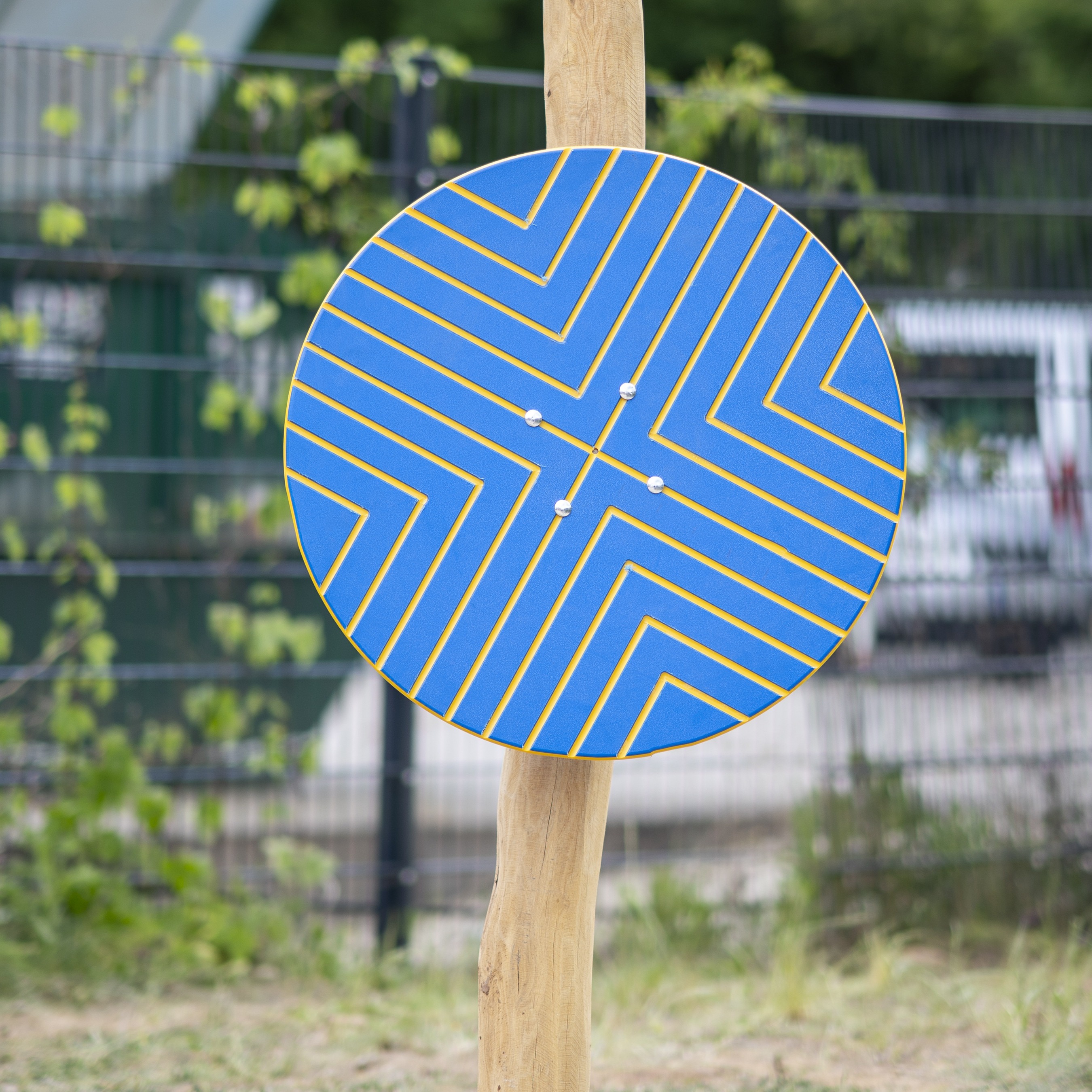 Blaues rundes Spielplatz-Element mit gelbem Labyrinth-Muster, montiert auf Holzpfosten