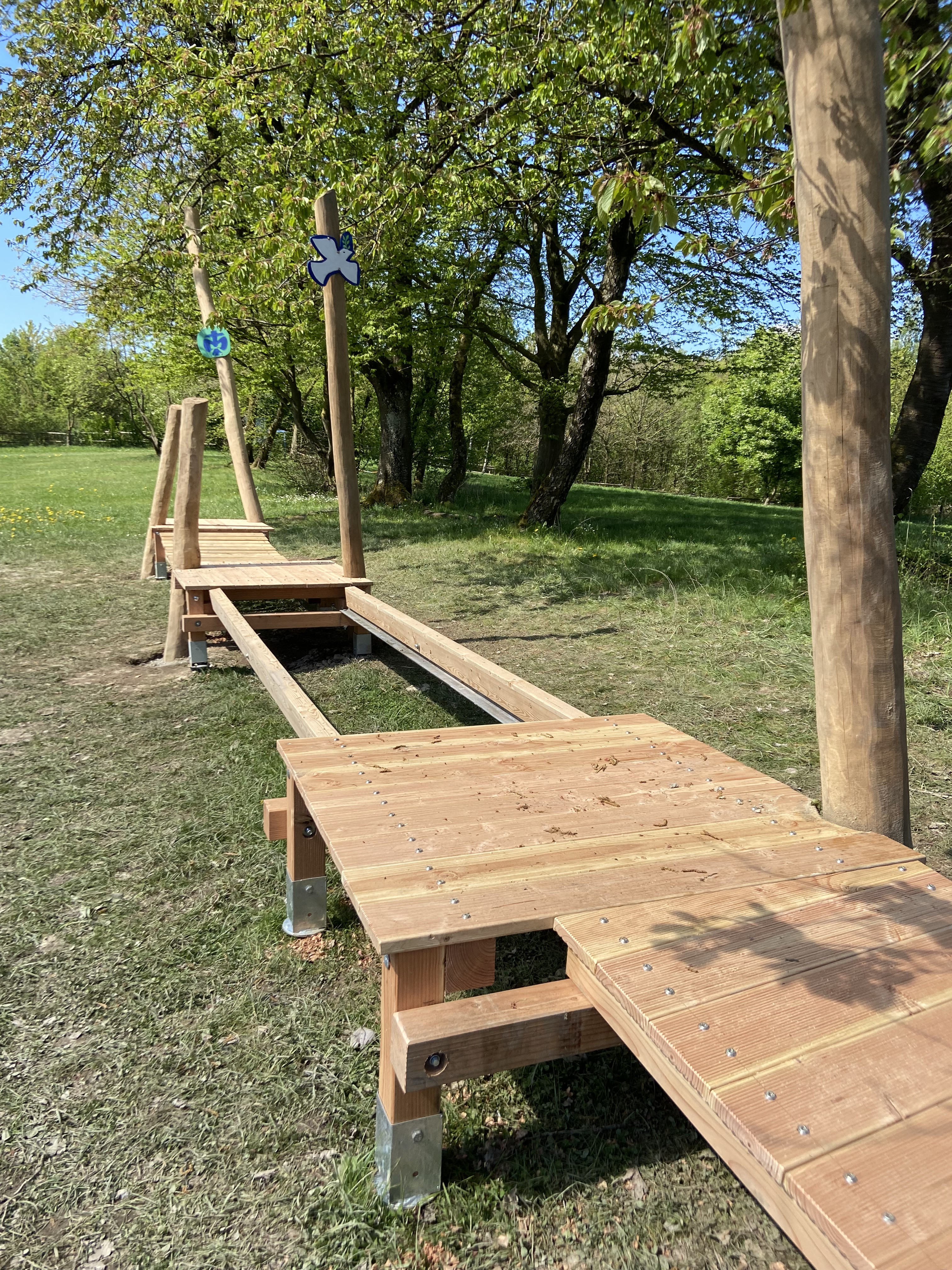 Holz-Balancierstrecke im Grünen auf einem Abenteuerspielplatz, aufgenommen bei sonnigem Wetter