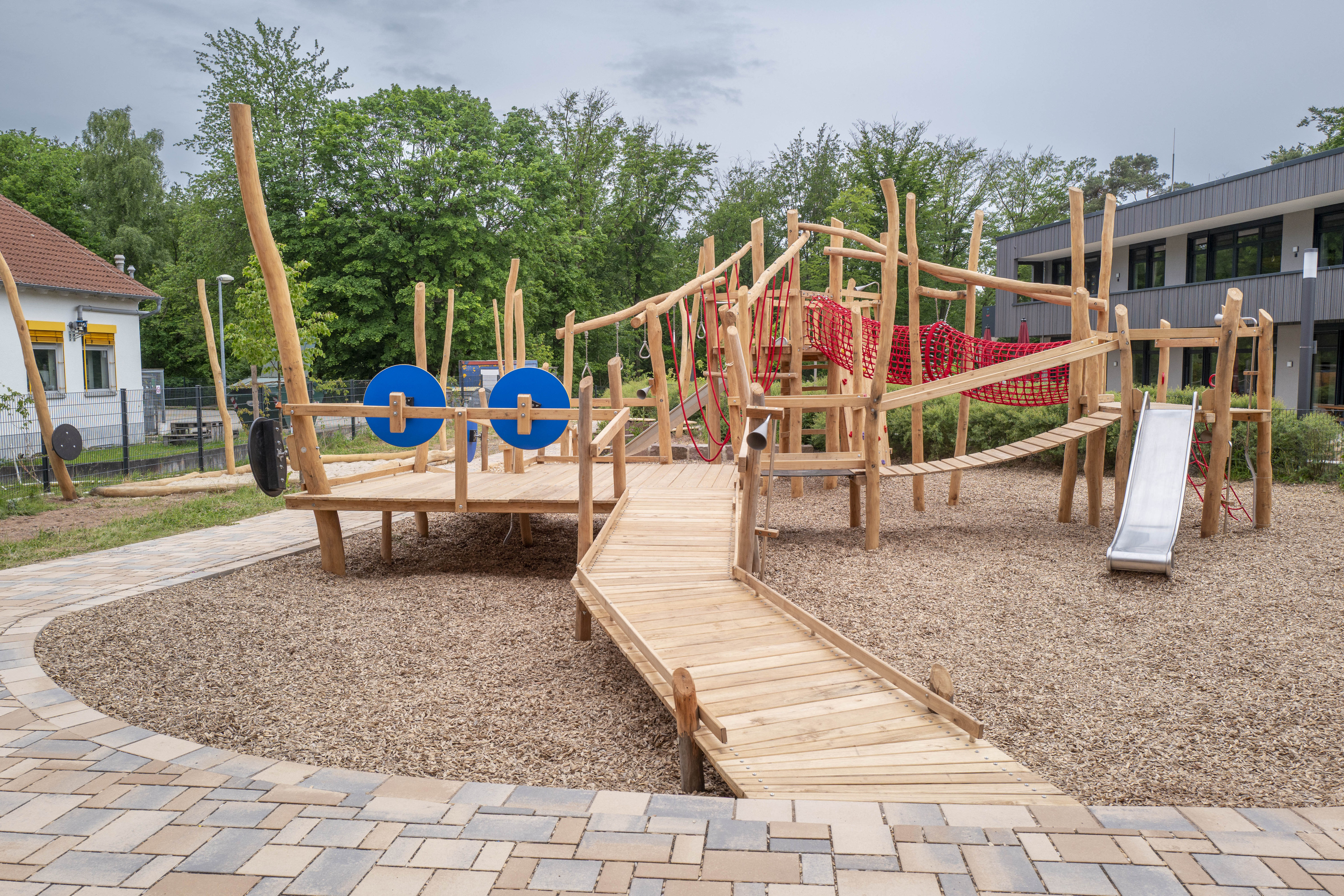 Moderner Abenteuerspielplatz aus Holz mit Kletterelementen und Balancierbrücke