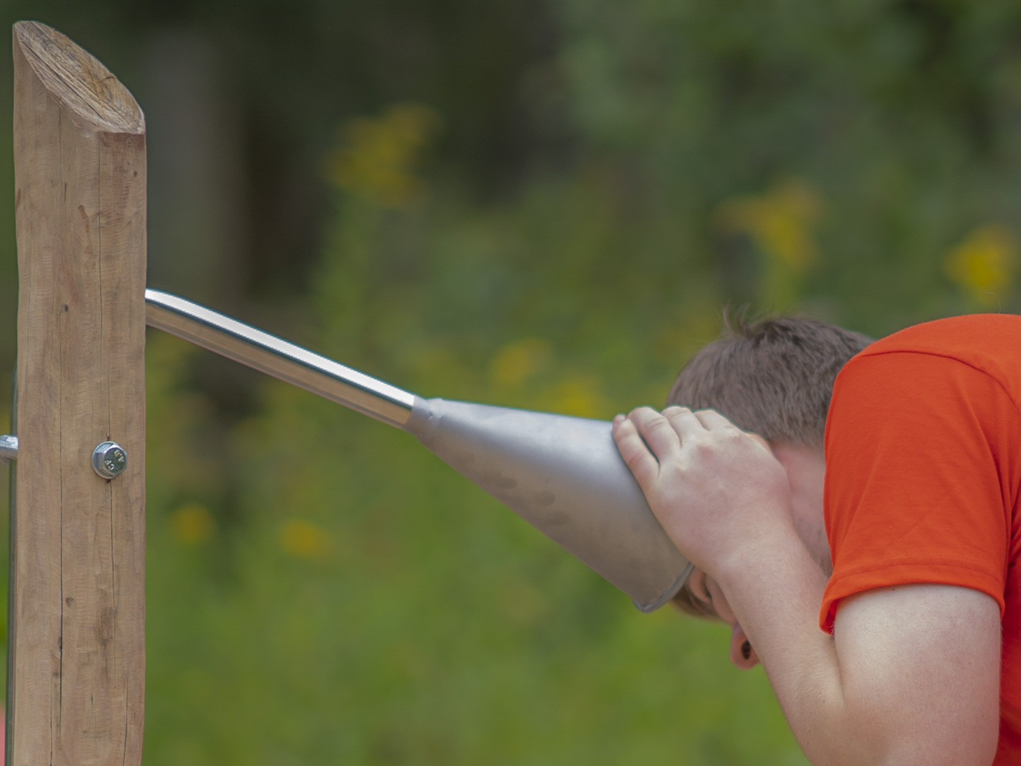 Junge betrachtet durch ein großes Fernrohr im Freien