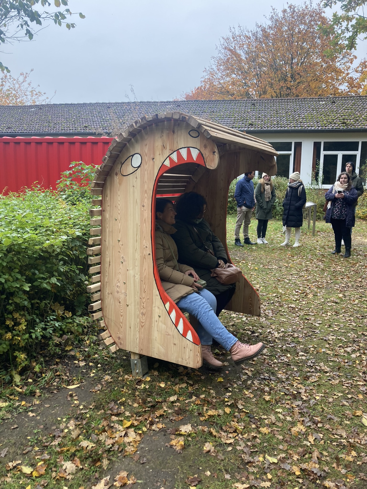 Holzbank in Form eines Monsters im Außenbereich mit Menschen im Herbst