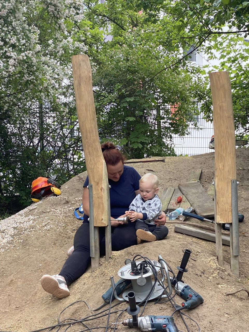 Frau mit Kleinkind beim gemeinsamen Handwerken auf einer Baustelle im Freien