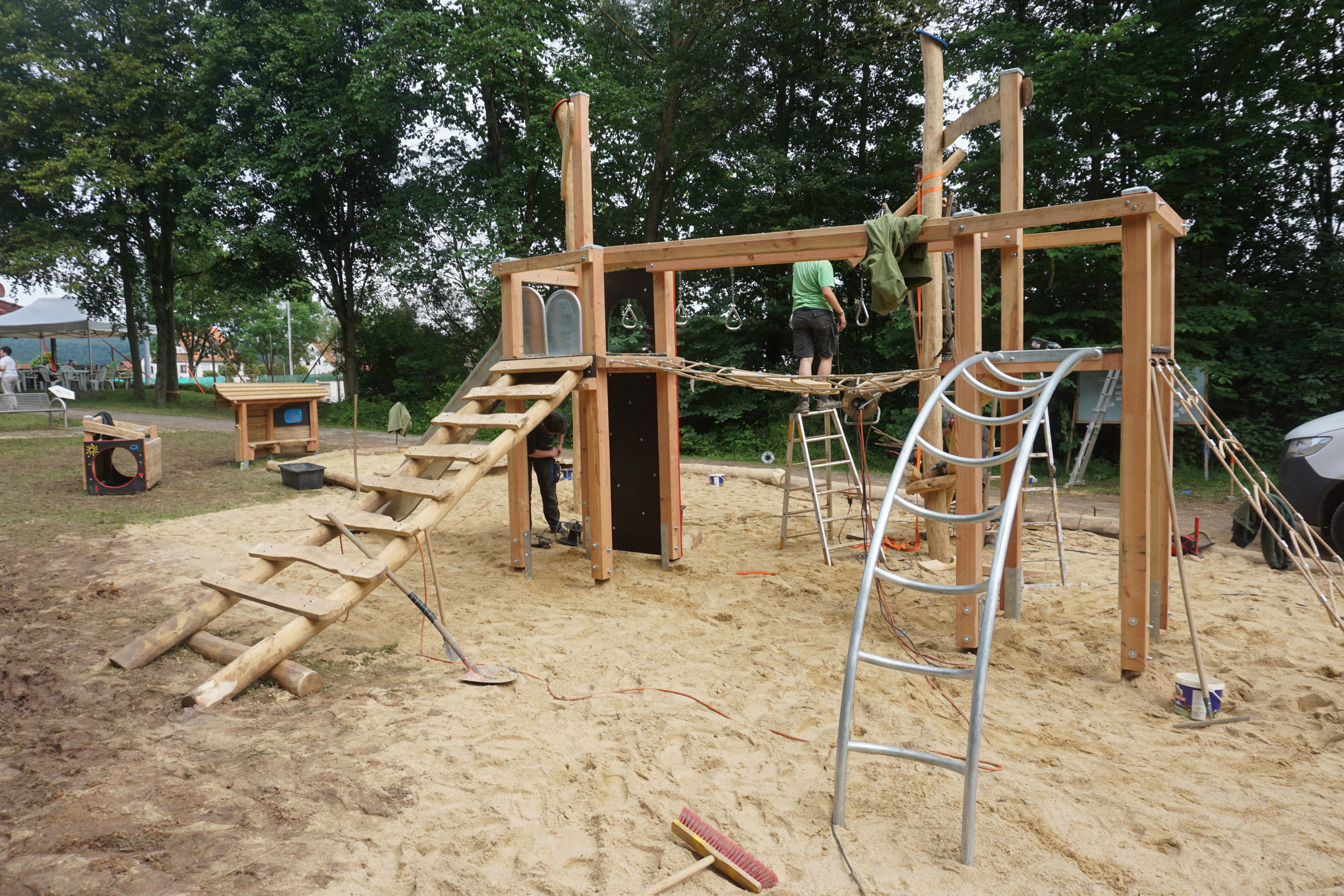 Bau eines modernen Holzspielplatzes mit Klettergerüst und Rutsche im Sandbereich