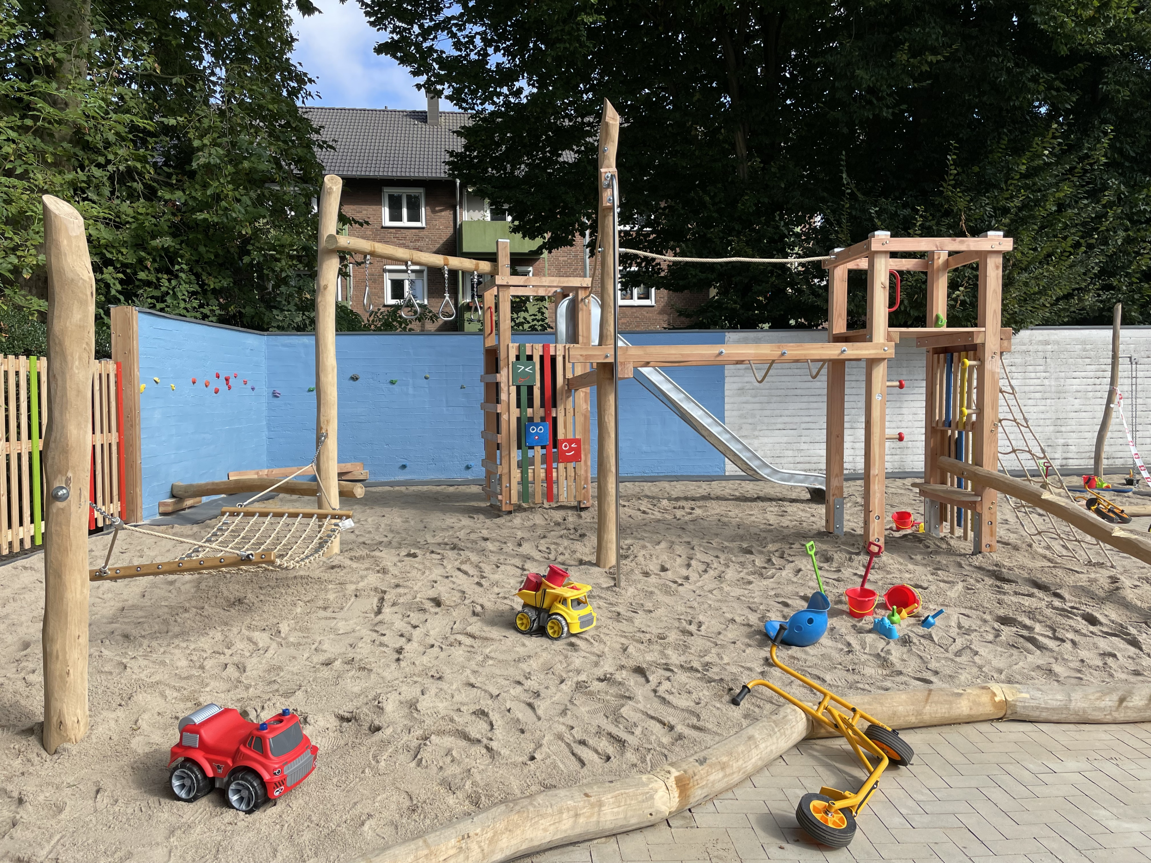 Moderner Spielplatz mit Sandkasten, Klettergerüst, Rutsche und Spielzeug im Freien