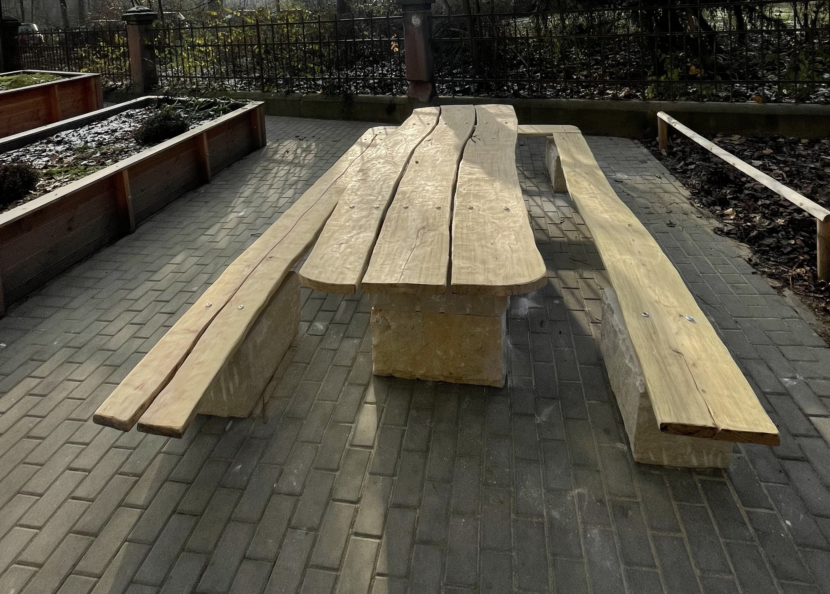 Rustikaler Holztisch mit Bänken auf Pflastersteinen im Freien