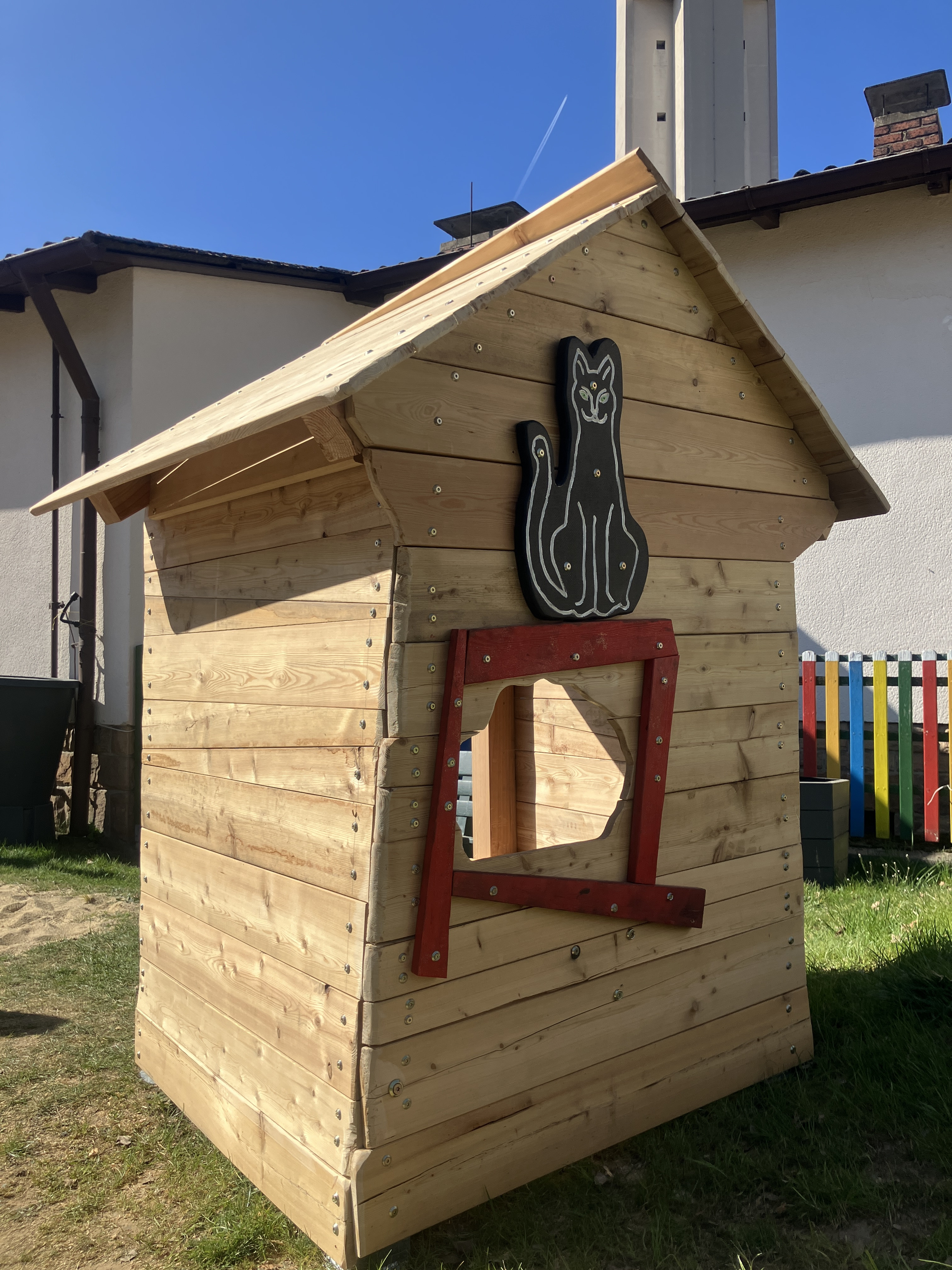 Holzhäuschen mit Katzenmotiv und schiefem Fenster im Garten