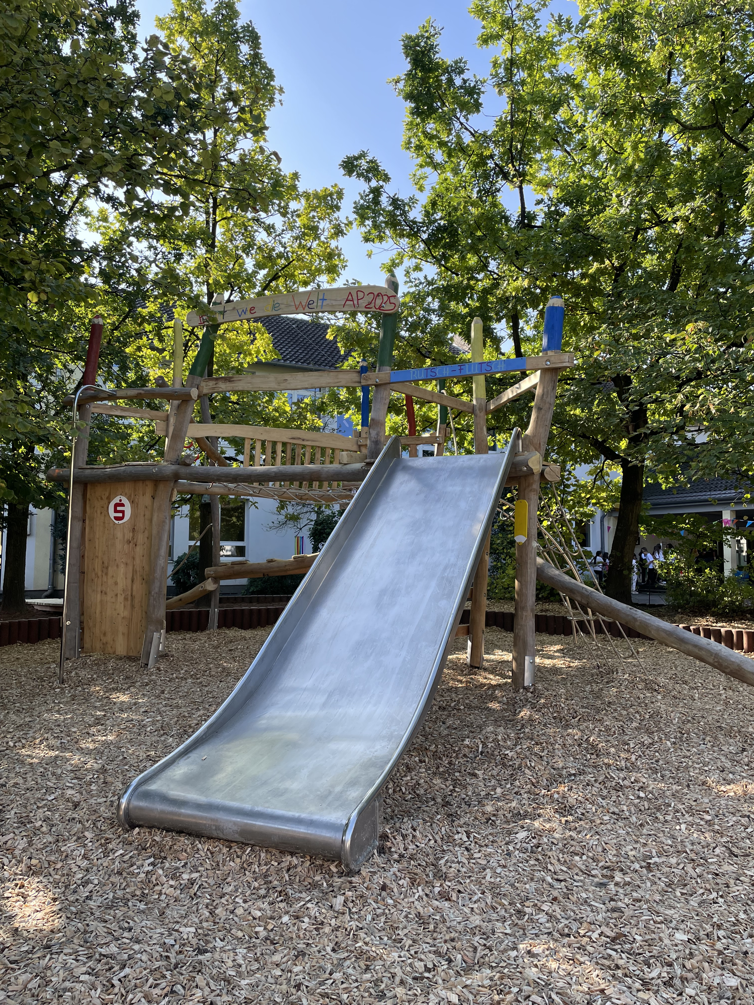 Abenteuerspielplatz mit Rutsche und Holzgerüst auf dem Spielplatz, sonniger Tag