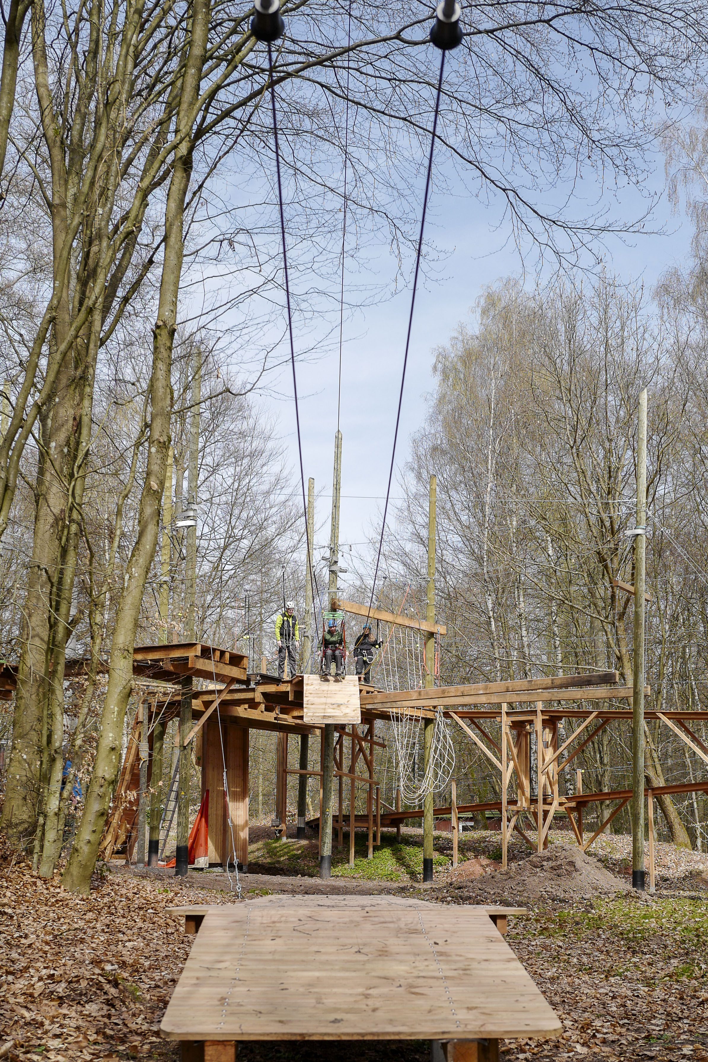 Kletterpark im Wald mit mehreren Personen auf einer Hochseilplattform