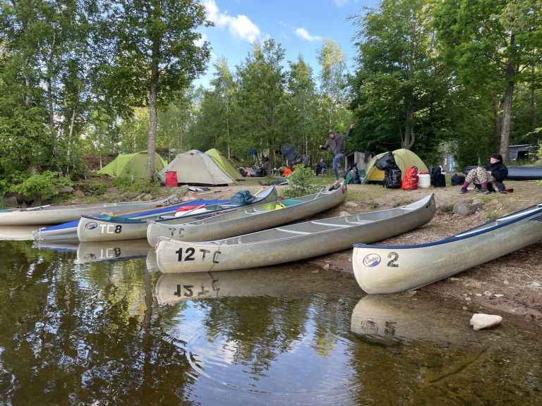 Kanus am Ufer mit Zeltlager im Hintergrund im Wald