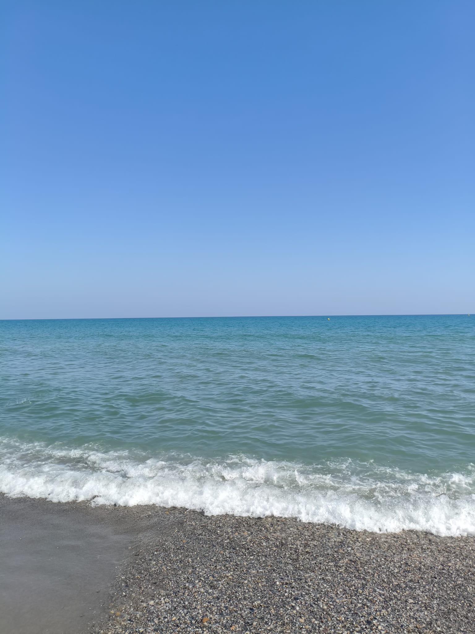 Klares Meer mit sanften Wellen und blauem Himmel am Strand