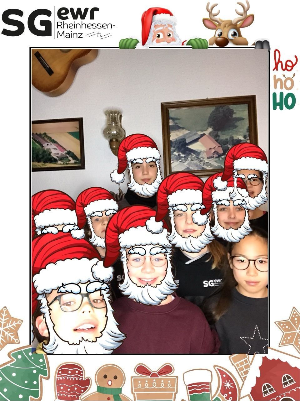 Gruppenfoto mit Weihnachtsmützen bei einer Weihnachtsfeier, Wanddekoration mit Gitarren und Bildern im Hintergrund