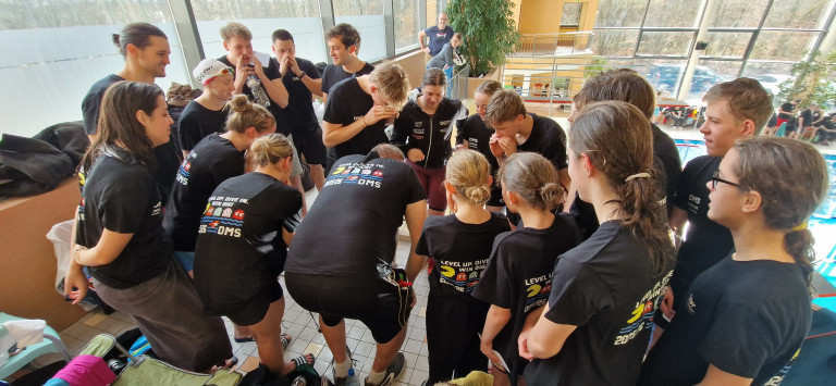 Schwimmteam bei der Besprechung vor dem Wettkampf im Hallenbad, DMS Event