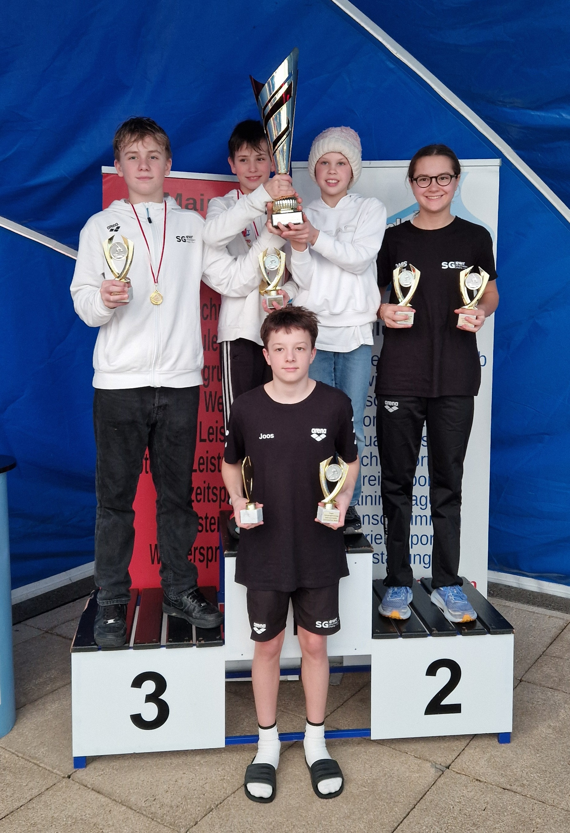 Schwimmwettkampf Siegerehrung mit Jugendlichen auf dem Podest und Pokalen