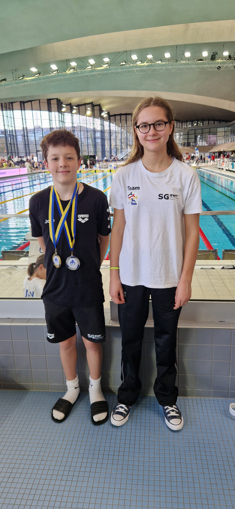Zwei junge Schwimmer der SG EWR Mainz mit Medaillen bei einem Schwimmwettkampf am Beckenrand