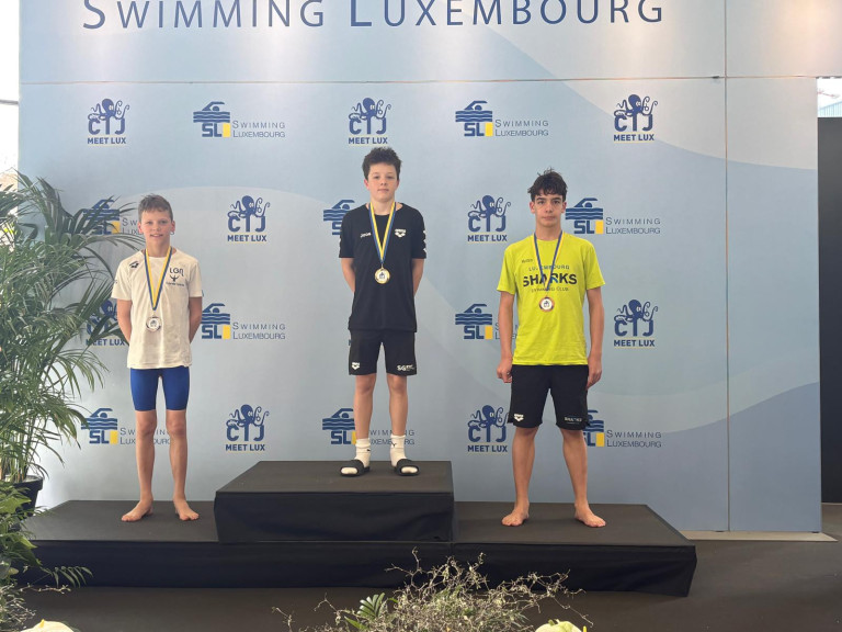 Siegerehrung Schwimmwettkampf in Luxemburg mit drei jungen Schwimmern auf dem Podest