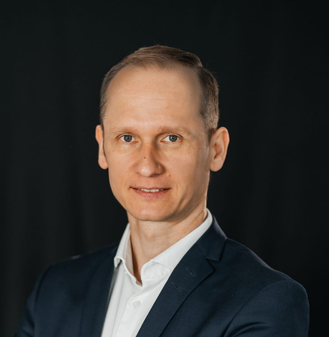 Business-Porträt eines Mannes im Anzug vor schwarzem Hintergrund, img-20260327-wa0003-quad