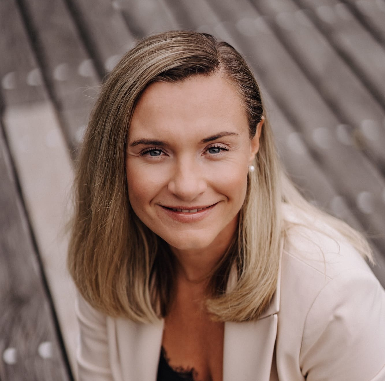 Porträt einer Frau im Business-Outfit auf Holzuntergrund, aufgenommen am 27.03.2026, quadratisches Bild