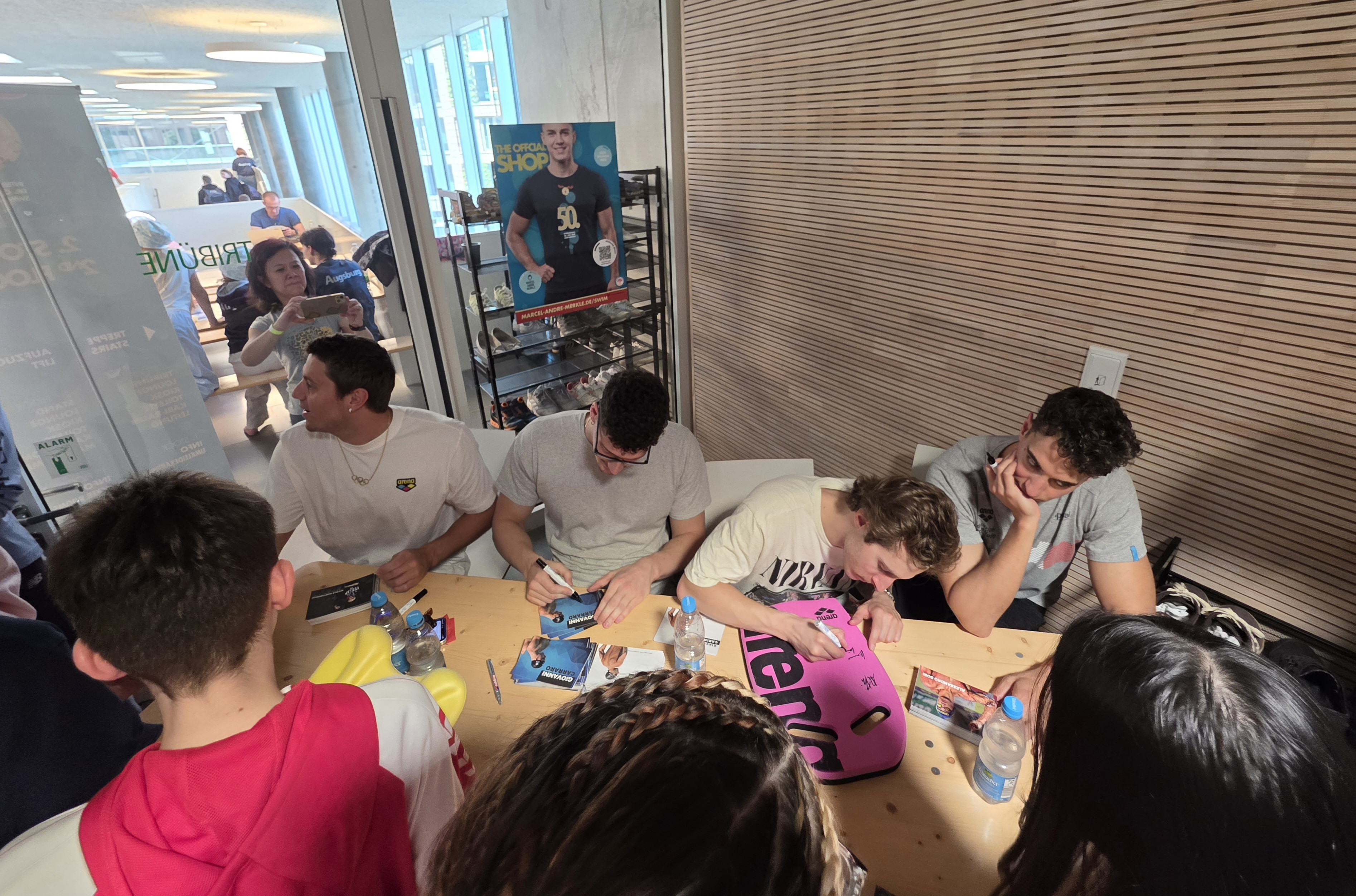 Autogrammstunde mit mehreren jungen Männern am Tisch, Fans warten auf Unterschriften, Aufnahme am 25.04.2026