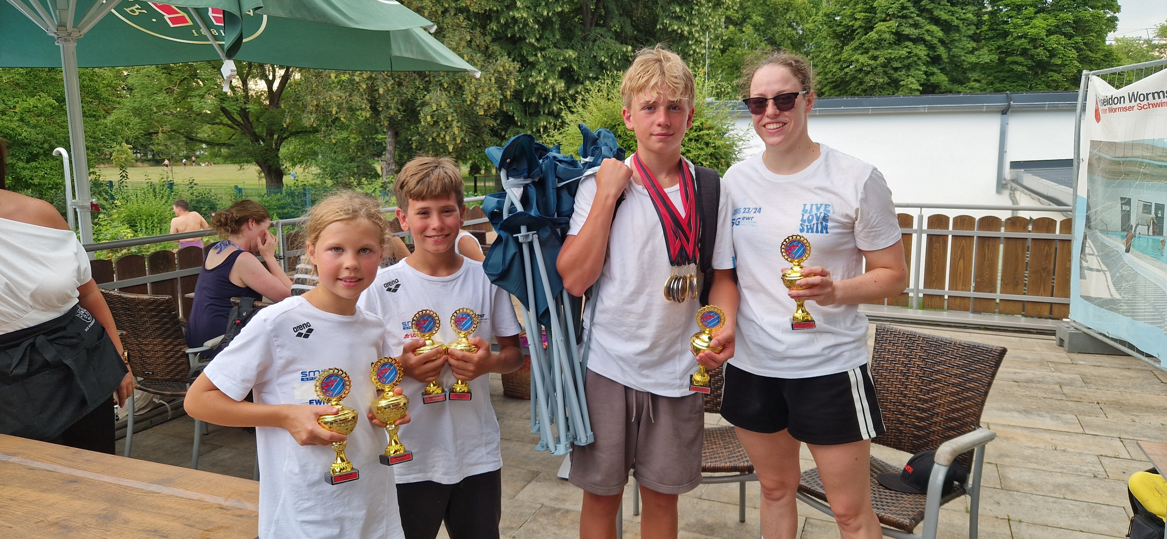 Gruppe von jungen Schwimmern und Trainerin mit Pokalen und Medaillen nach einem Schwimmwettbewerb am 21.06.2026