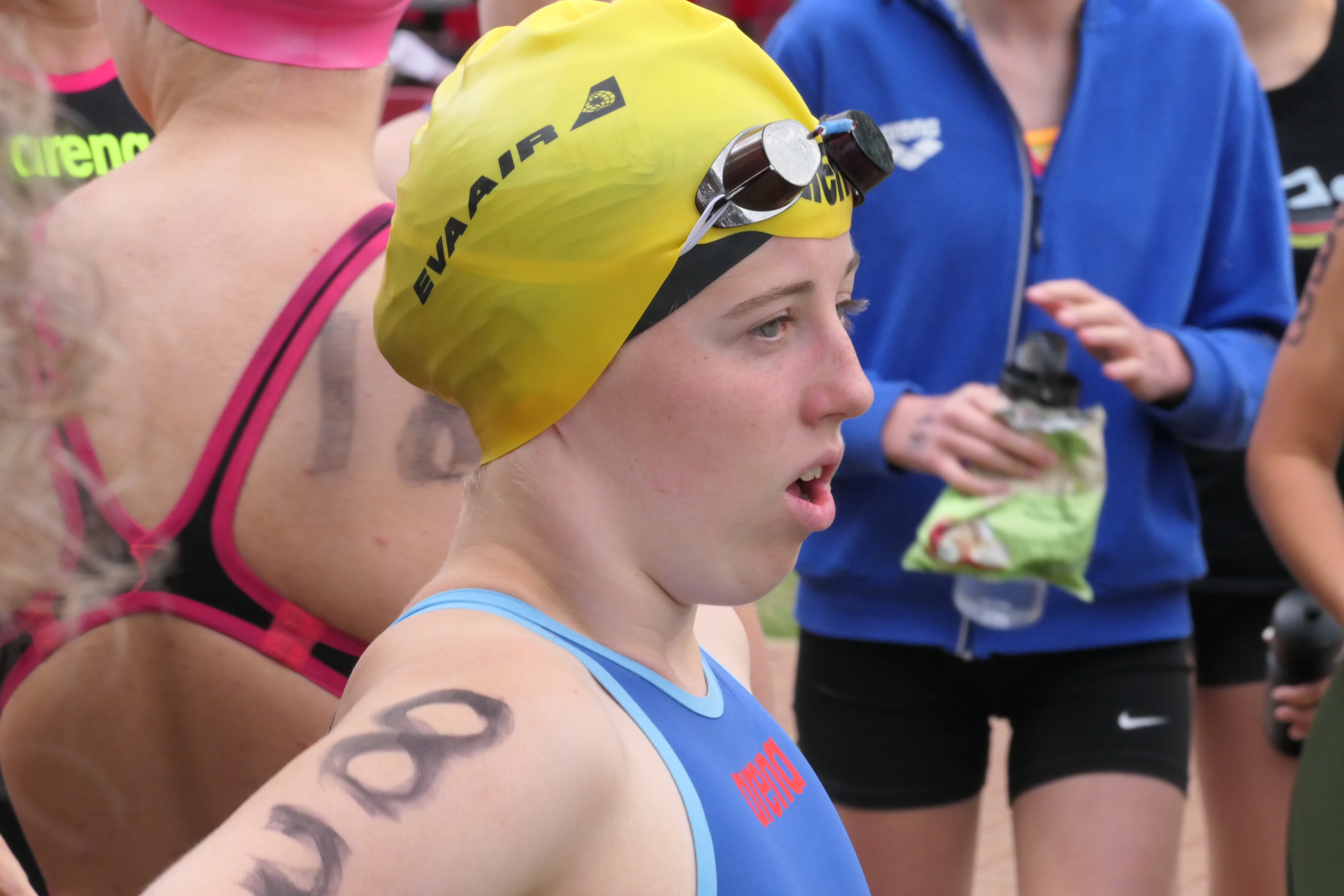 Triathletin mit gelber EVA AIR Badekappe und Startnummer bereitet sich auf das Schwimmen vor