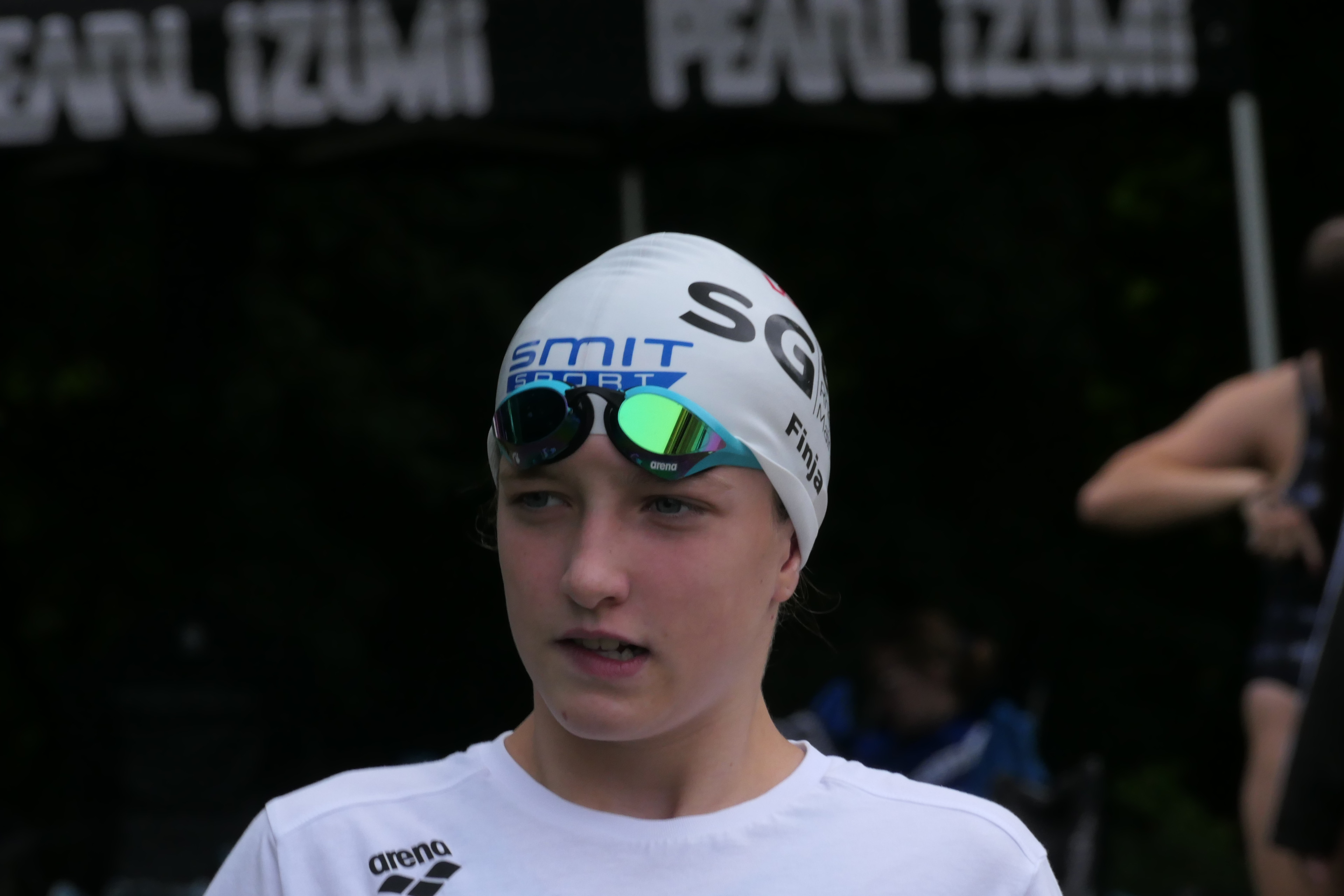 Junge Schwimmerin mit Badekappe und Schwimmbrille beim Wettkampf