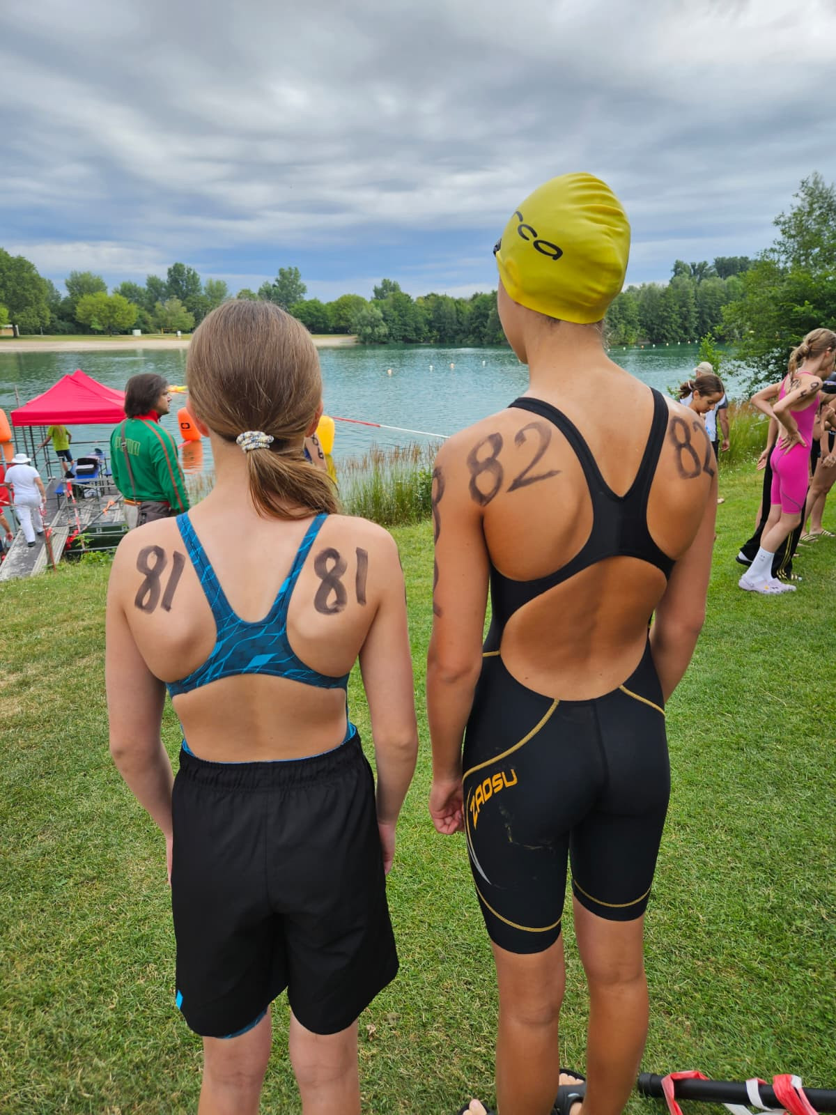 Zwei junge Schwimmerinnen mit Startnummern 81 und 82 beim Triathlon am Seeufer, bereit für den Wettkampf