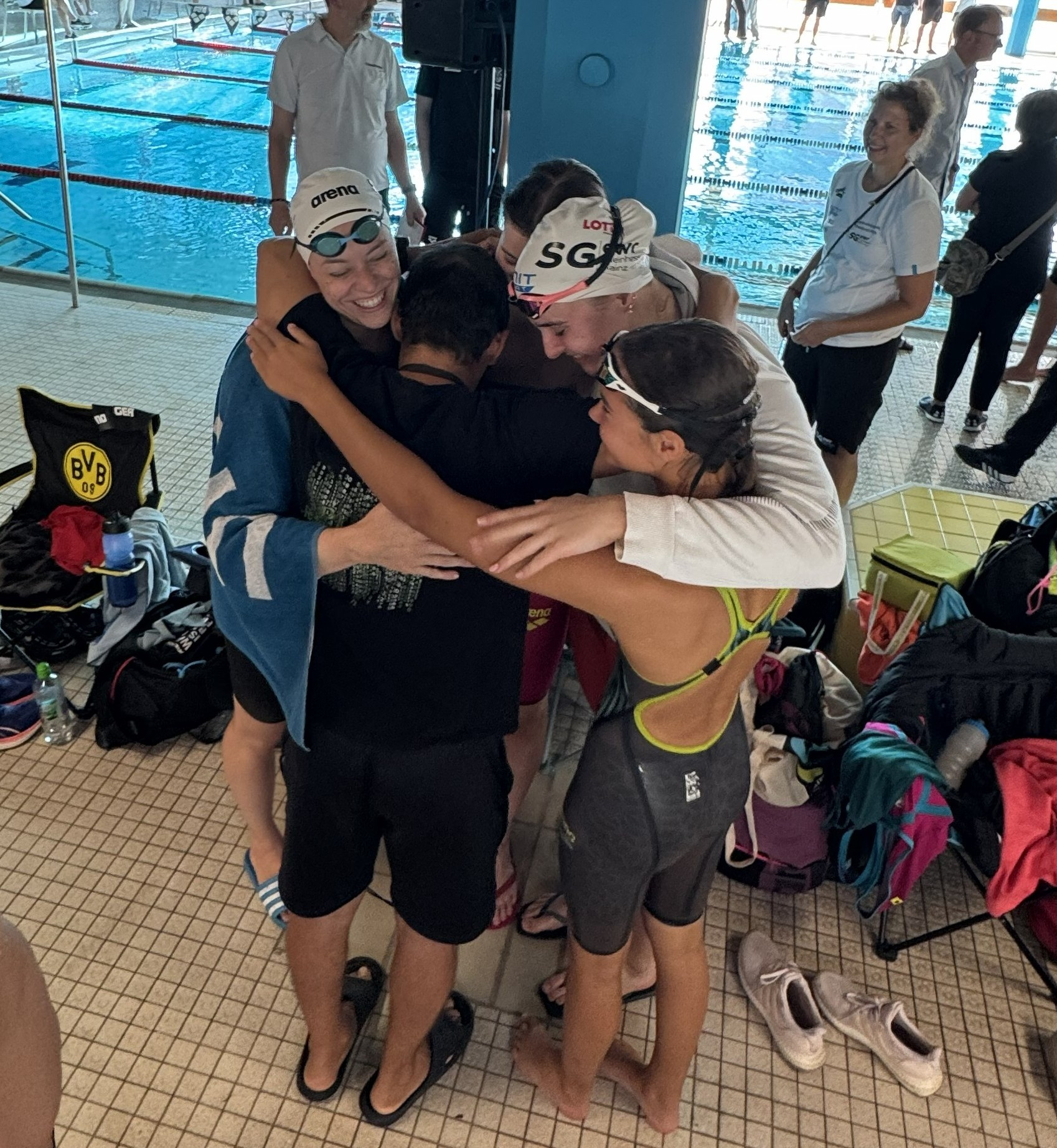 Schwimmteam feiert gemeinsam am Beckenrand nach einem Wettkampf