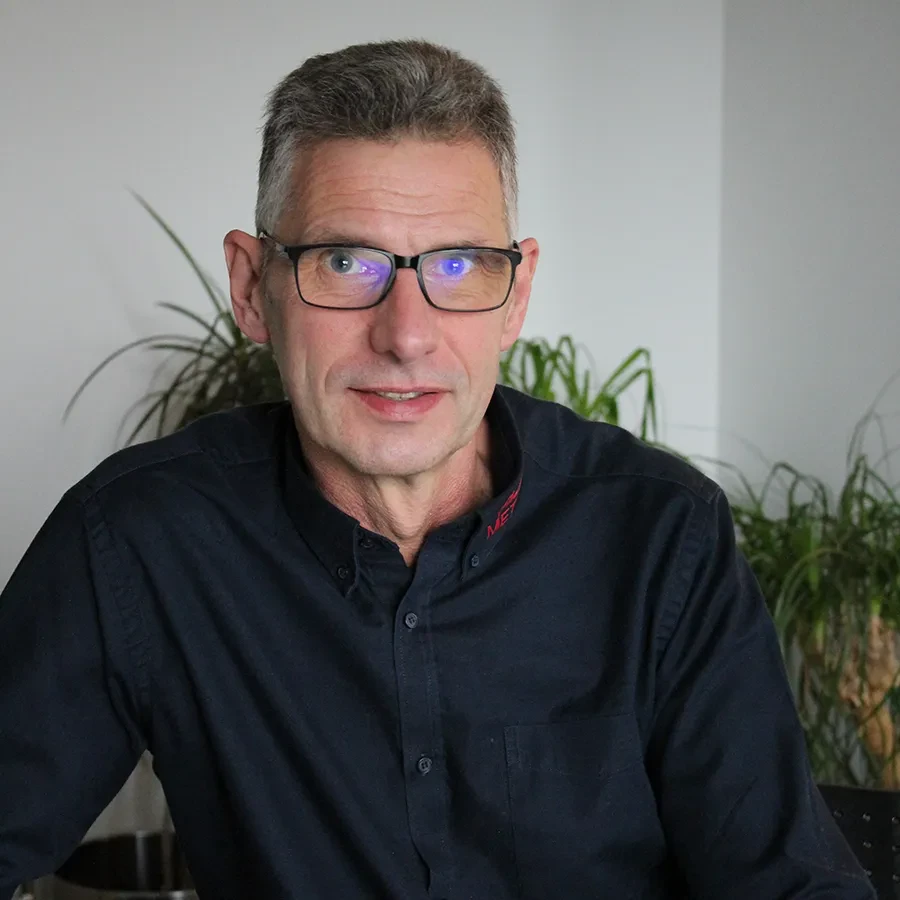 Olaf Götz sitzt im Büro mit dunklem Hemd