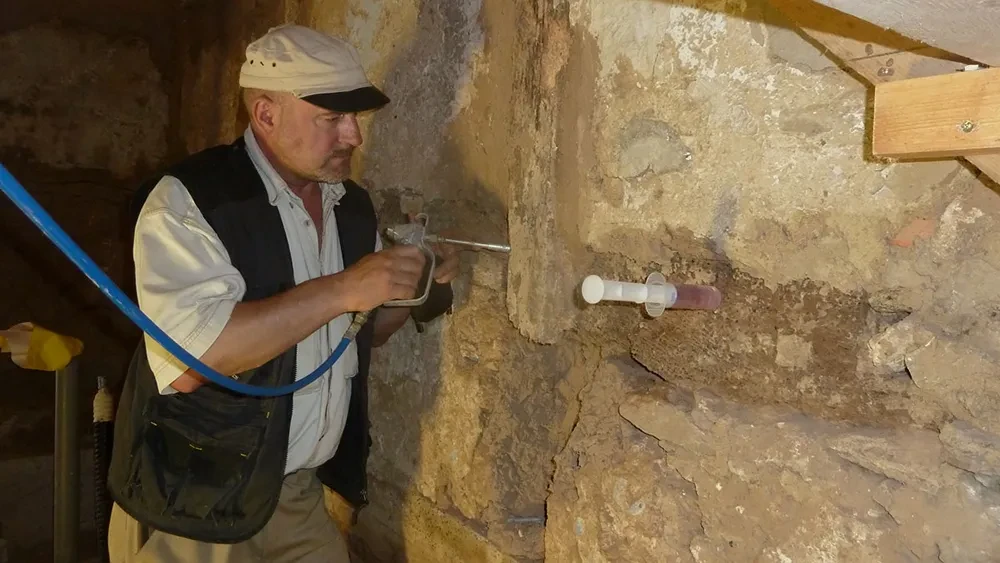 Heiko Schaper bei der Mauertrockenlegung mit Injektionstechnik an einer alten Steinmauer