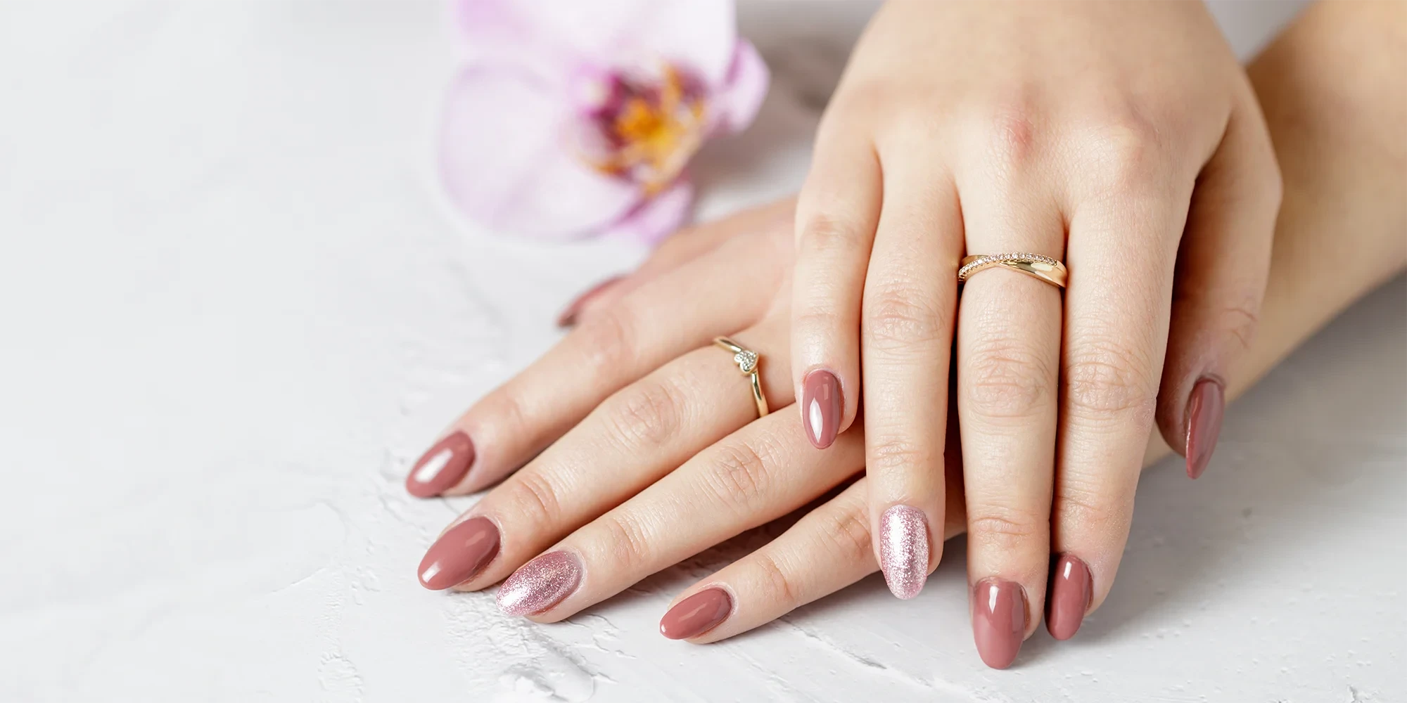 Header Maniküre – gepflegte Hände mit rosa Nagellack und Glitzereffekt