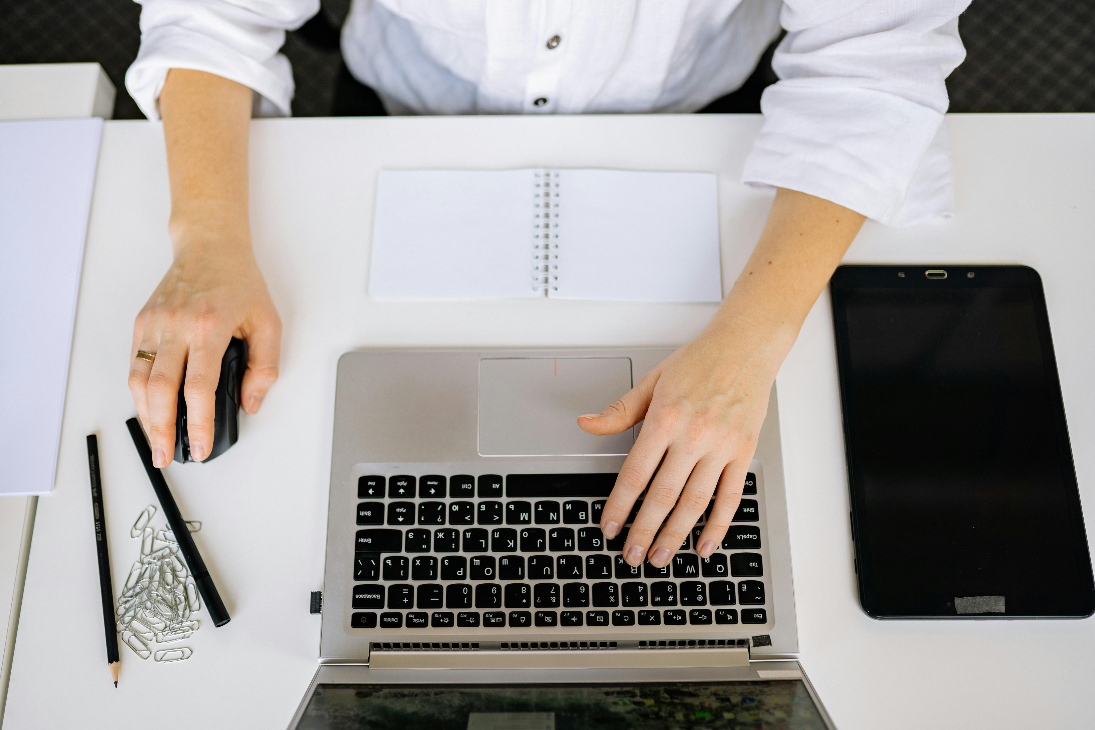 Person mit Laptop am Schreibtisch, arbeitet am Computer