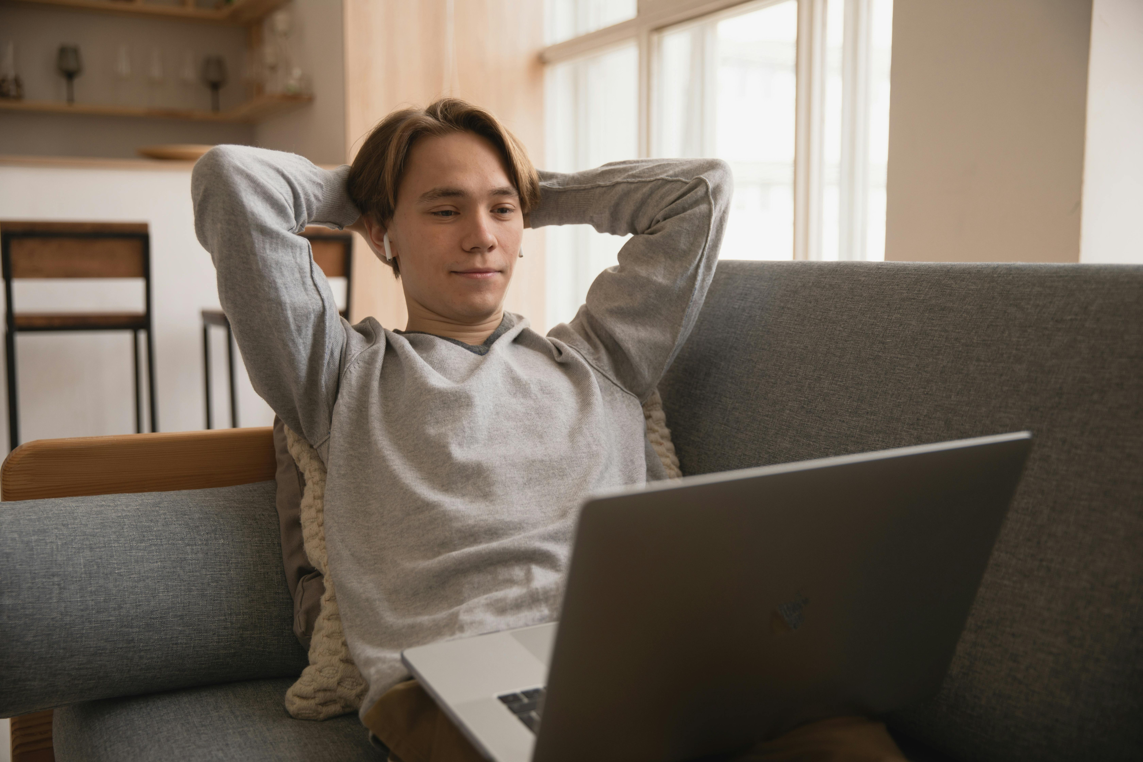 Person mit Laptop entspannt auf dem Sofa im Wohnzimmer