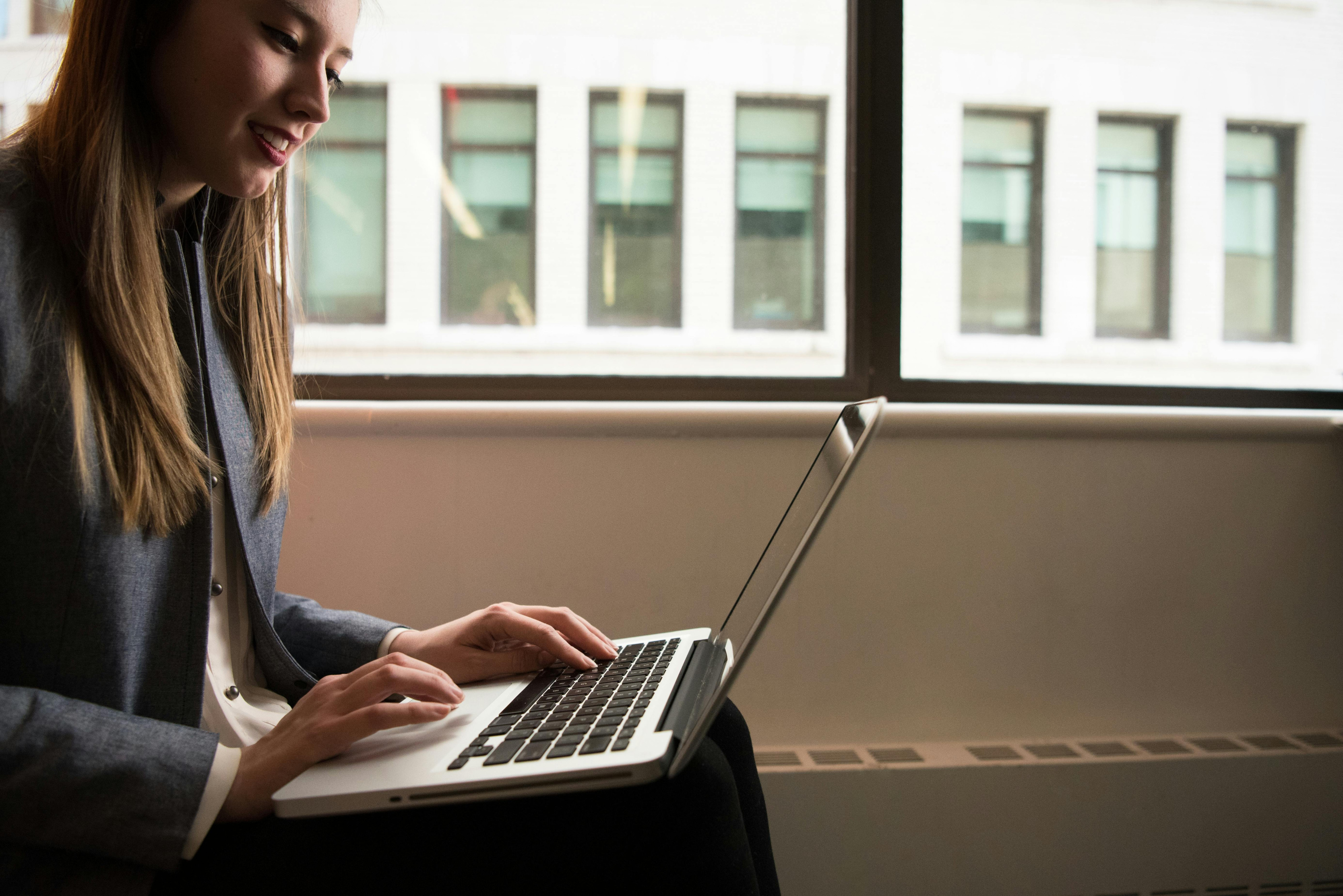 Person mit Computer arbeitet am Laptop am Fenster