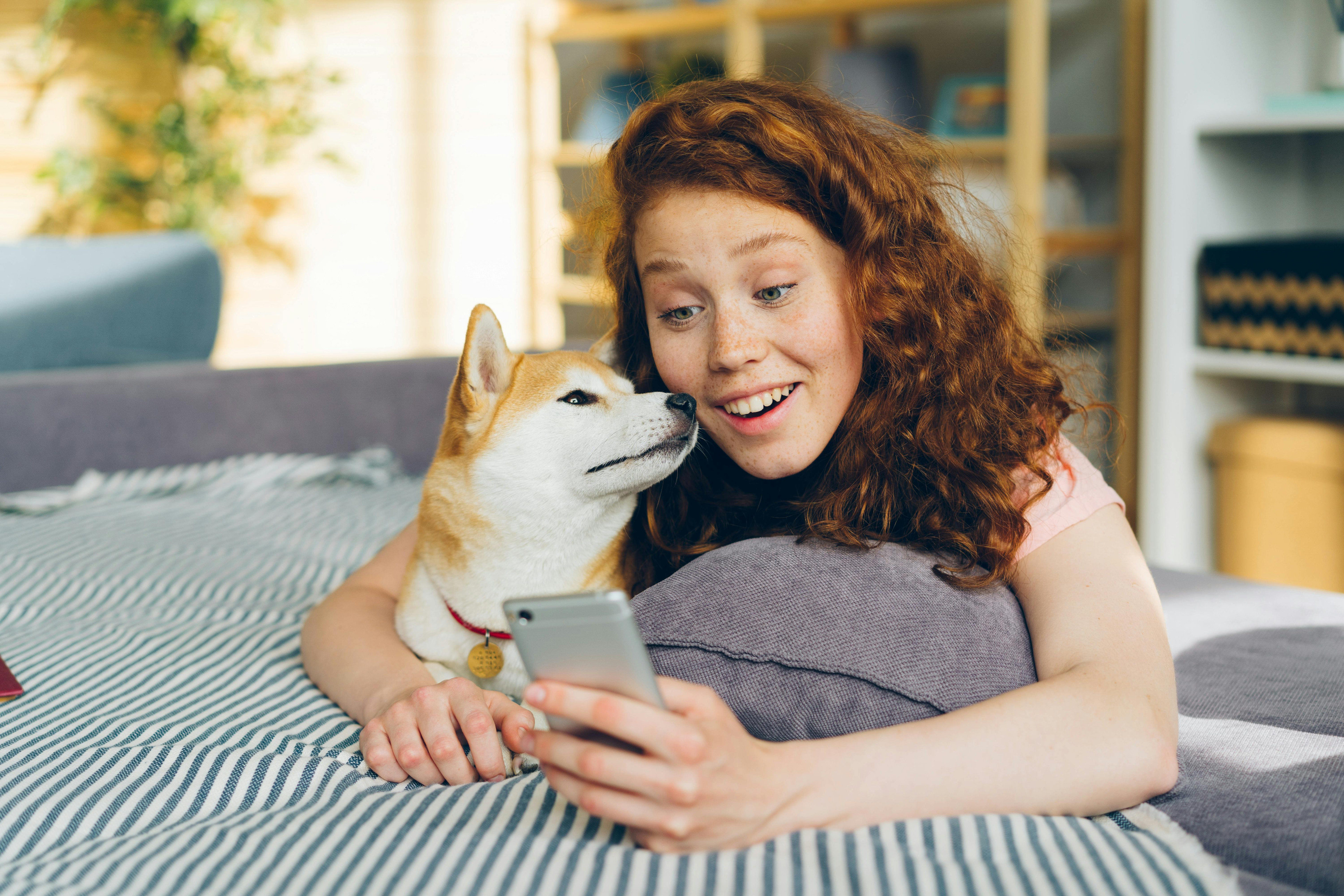Person mit Haustier und Smartphone auf dem Sofa
