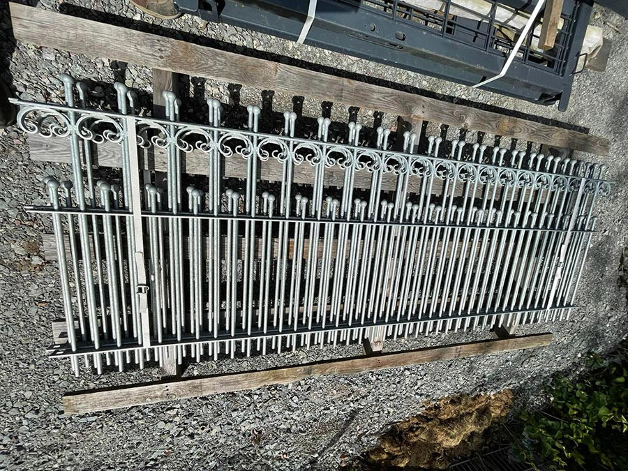 Schmiedeeisenzaun 7 Meter lang mit dekorativen Elementen auf Kiesuntergrund