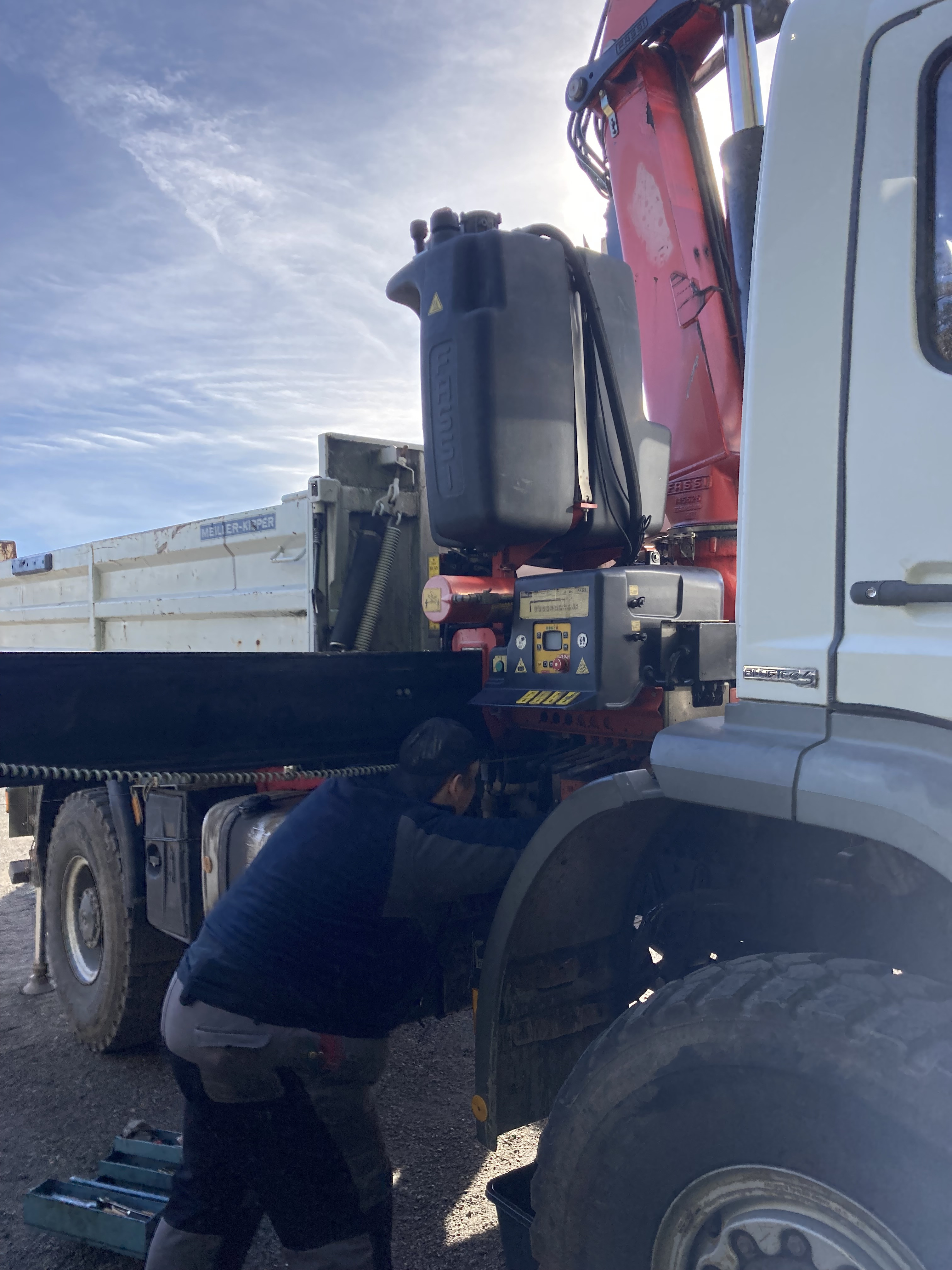 Arbeiter bei Wartung eines LKW-Krans auf Baustelle